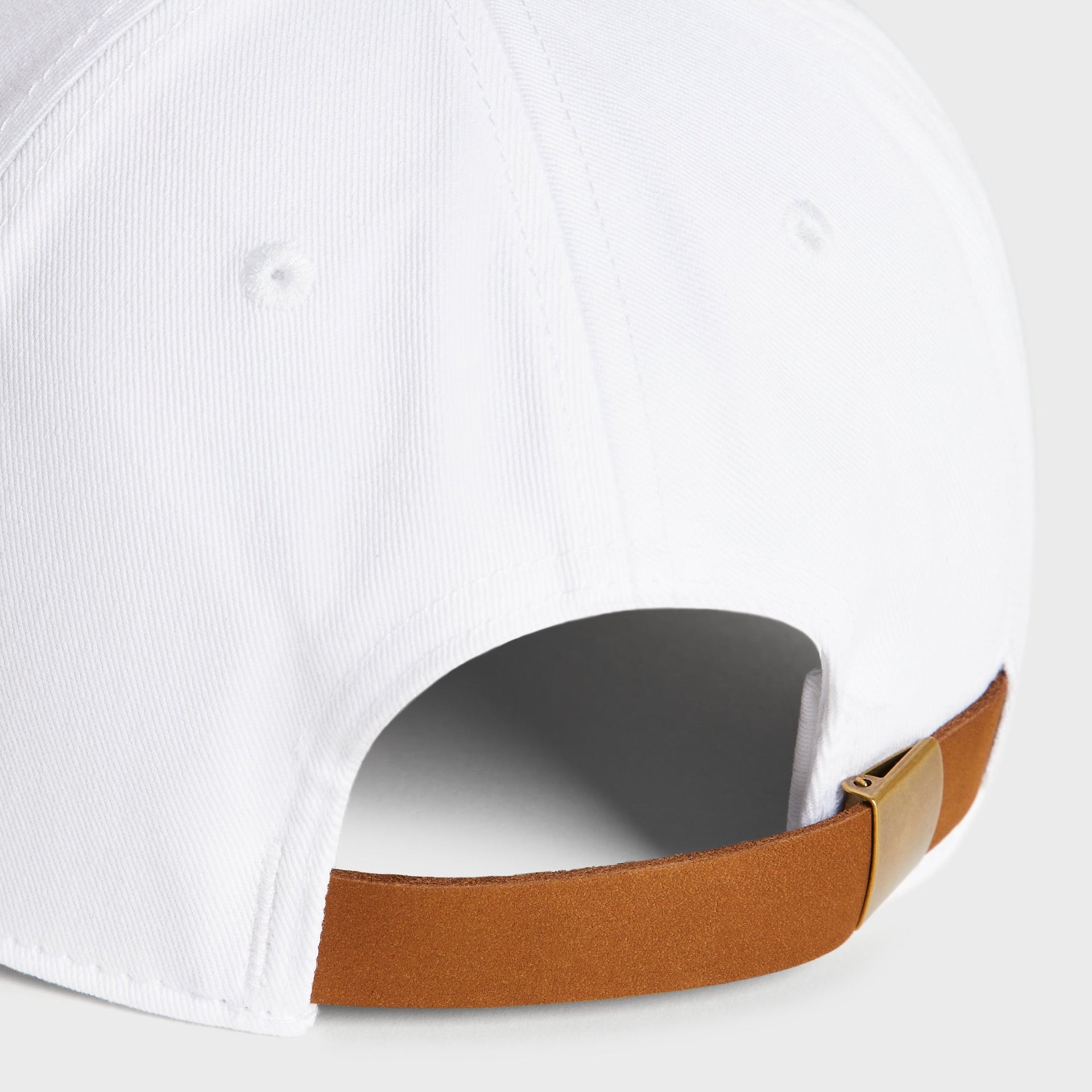 Close-up of the tan leather strap and brass buckle on the Kith Two Tone classic cap