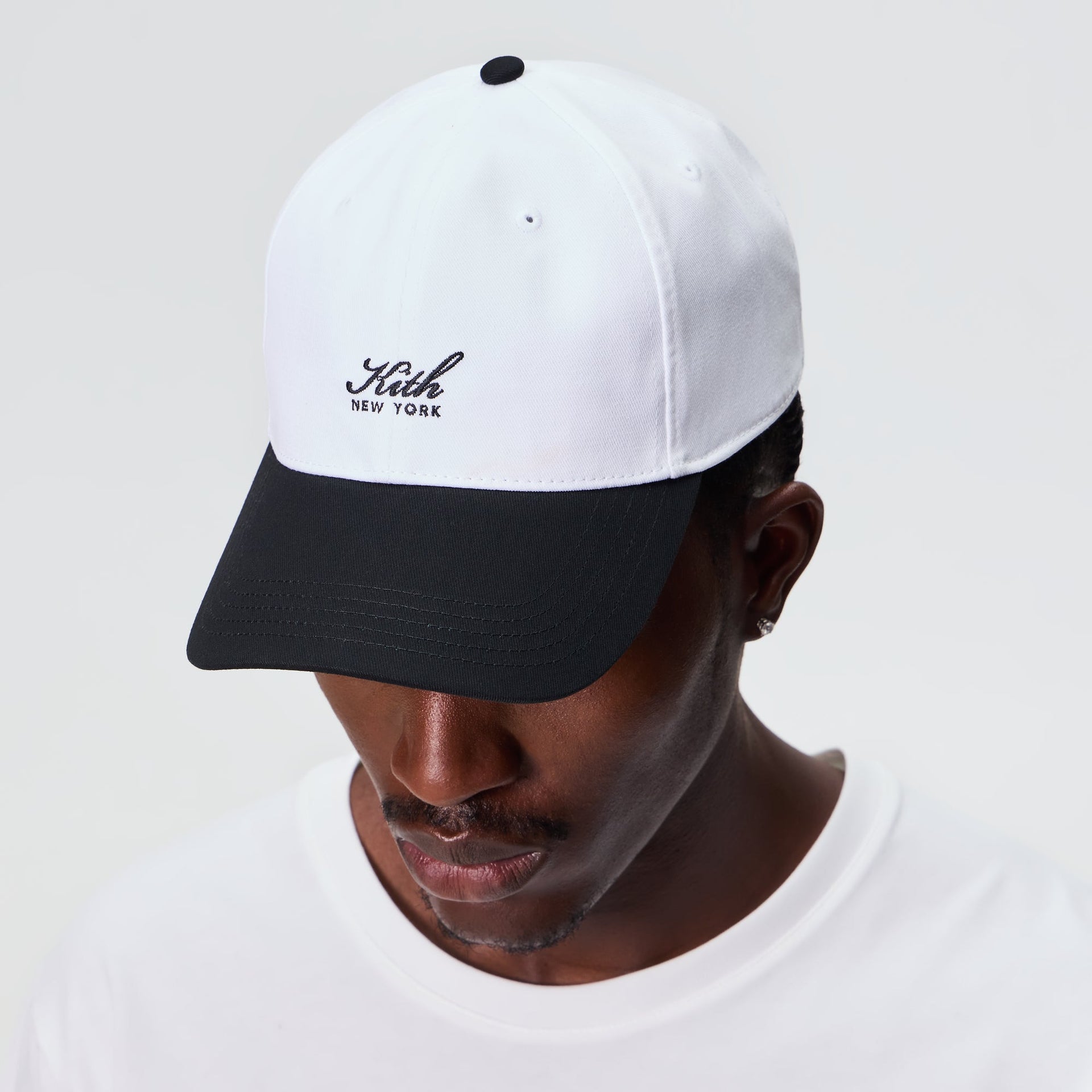 Man wearing the Kith Script Two Tone classic cap in white with black brim