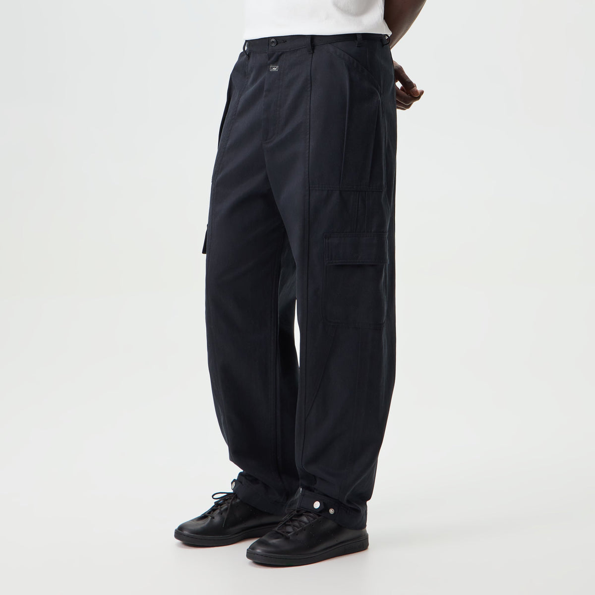 Man wearing black Kith Washed Herringbone Twill Gus cargo trousers, side view