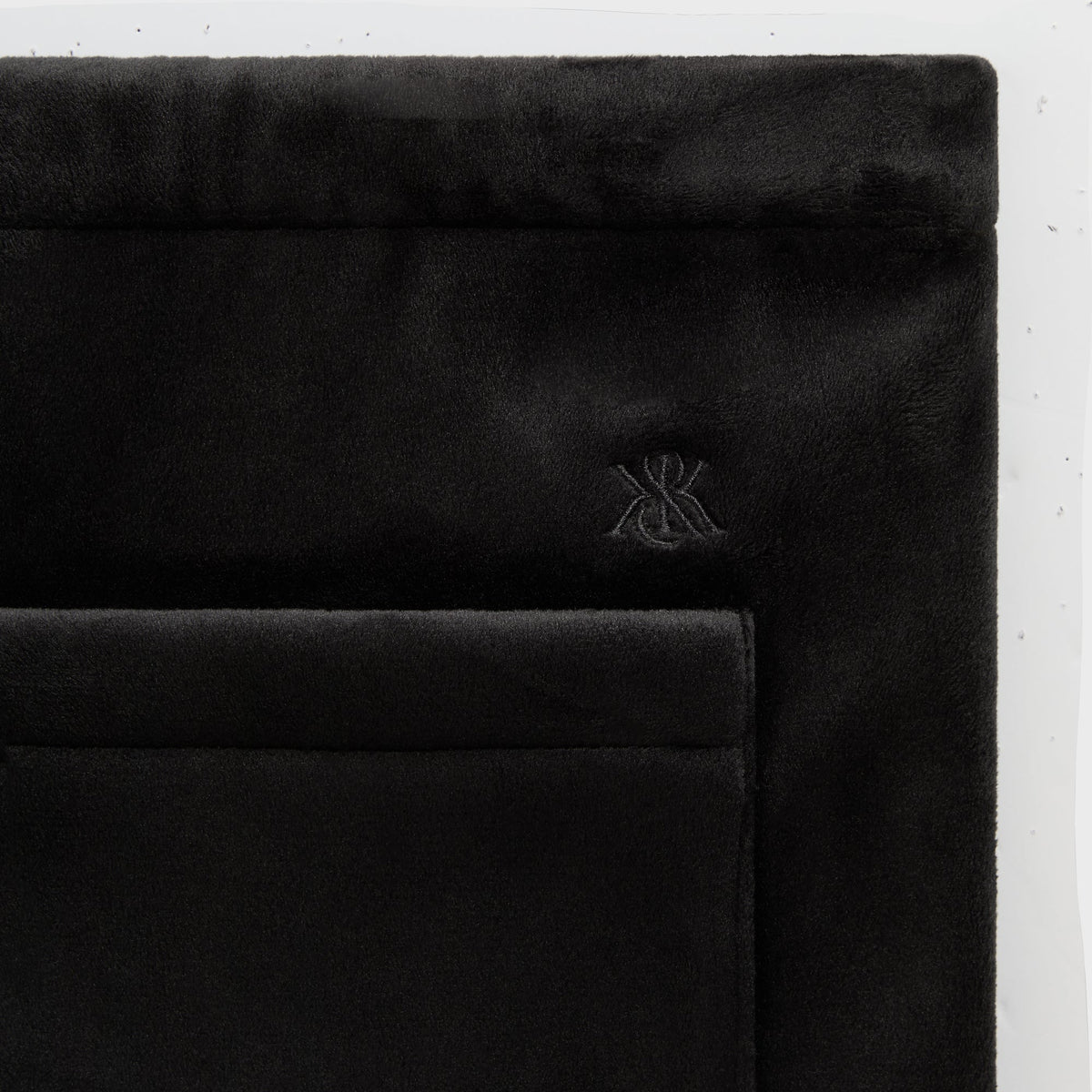 Close-up of the tonal XK monogram on the black Plush Double Fleece Grayson sweatpant