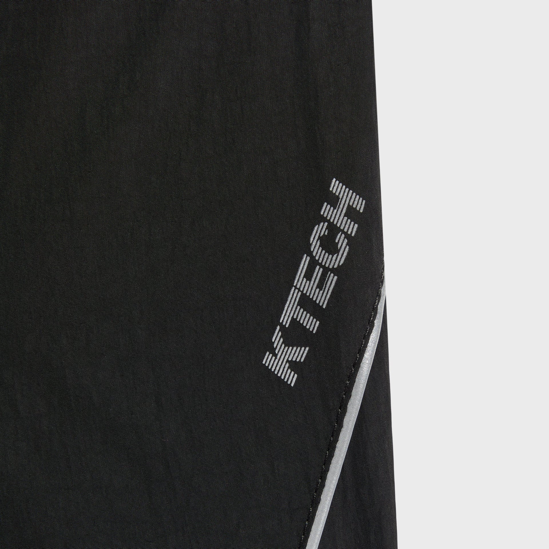 Close-up of the reflective KTECH logo on the side seam of the Kith Nylon Bolt pant