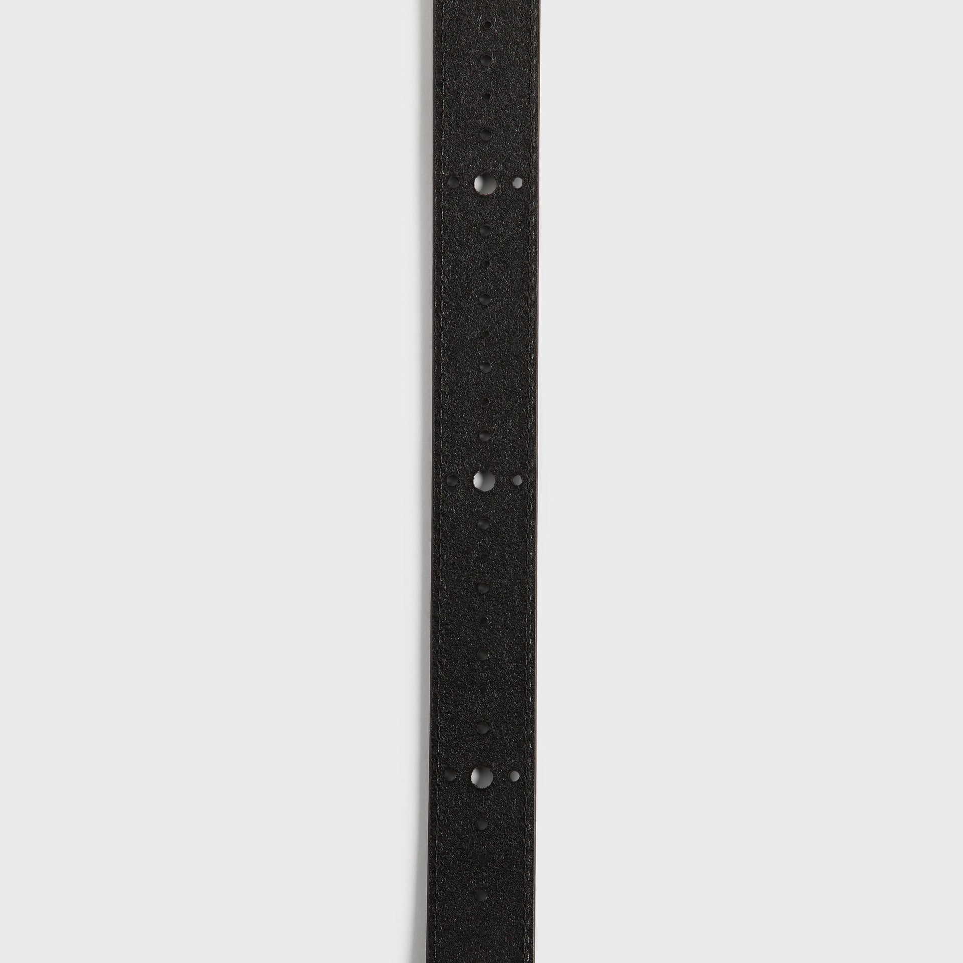 Kith Studded Leather Belt in Black, macro vertical close-up of the perforated adjustment holes on the strap