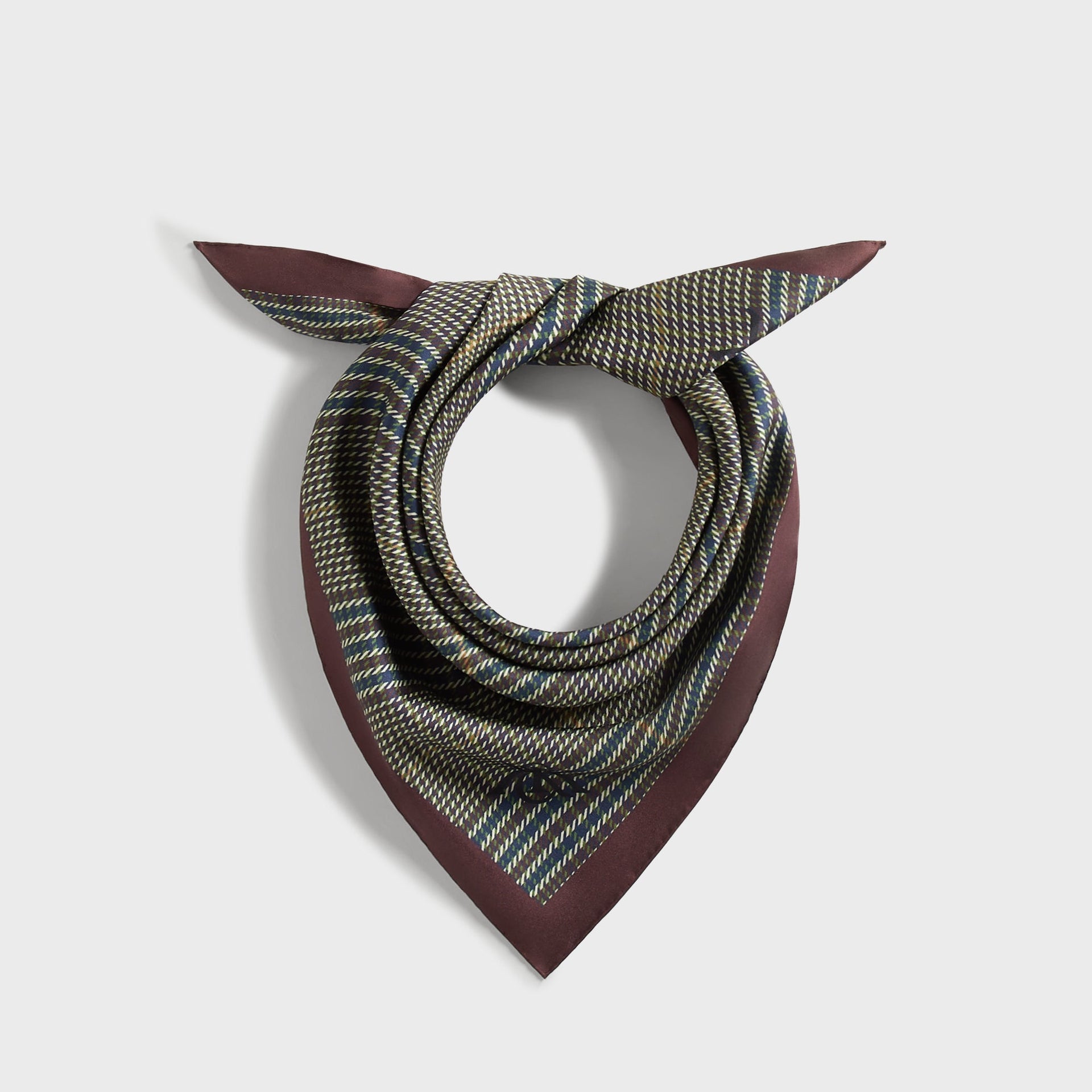 Kith Printed Silk Scarf in Kindling, rolled and knotted into a neckerchief showing burgundy border and houndstooth plaid