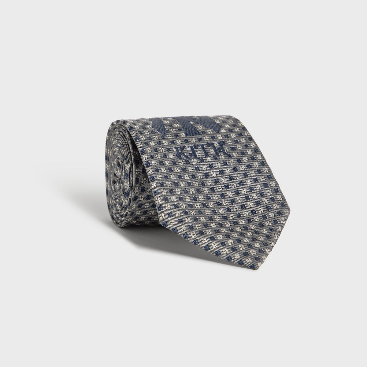 Kith x New York Yankees Skyscraper tie rolled up, showing grey dot pattern and NY logo