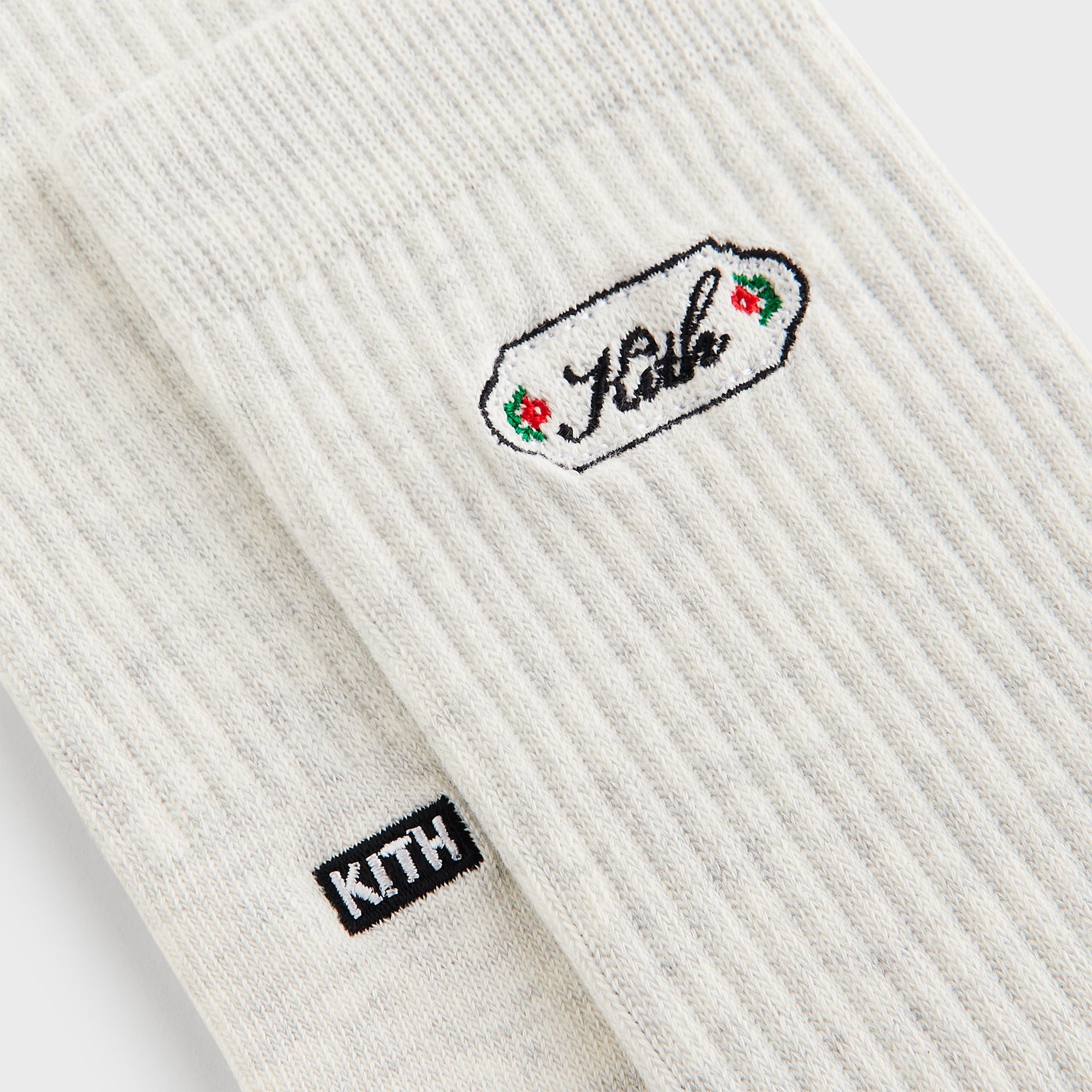 Close-up of the oatmeal heather crew sock with the Kith script plaque logo embroidered in red and green florals