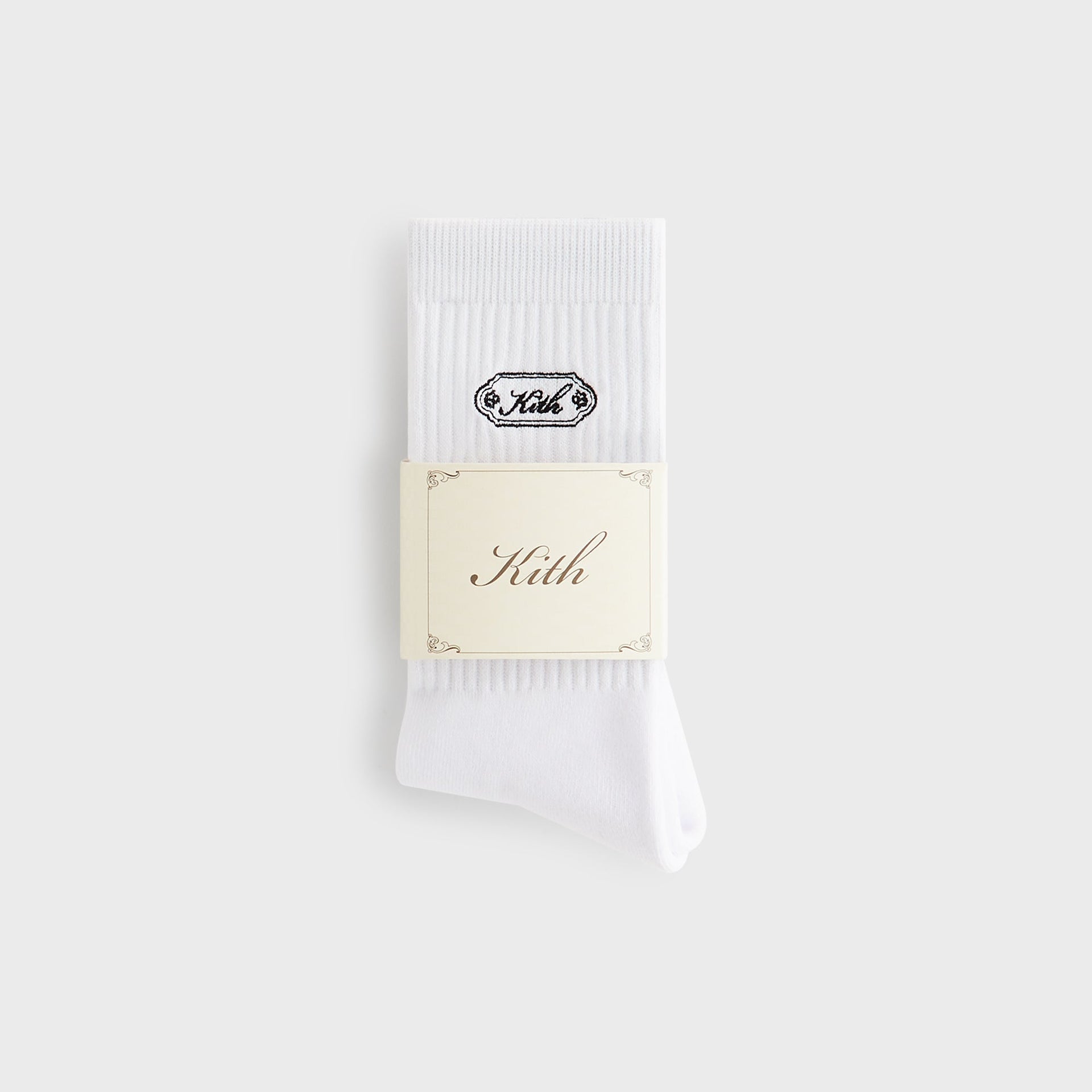 Folded white Kith crew sock with branded cream paper wrap band reading Kith