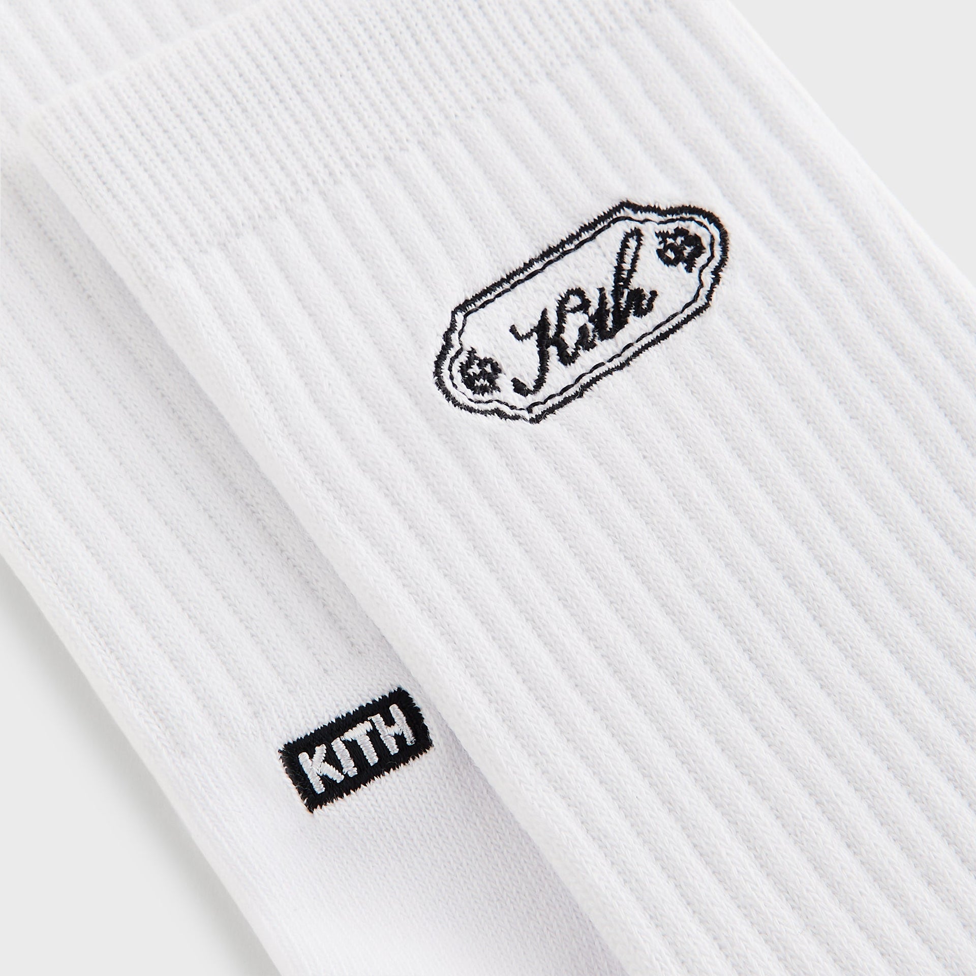 Close-up of the white crew sock showing the embroidered Kith script plaque and KITH box logo