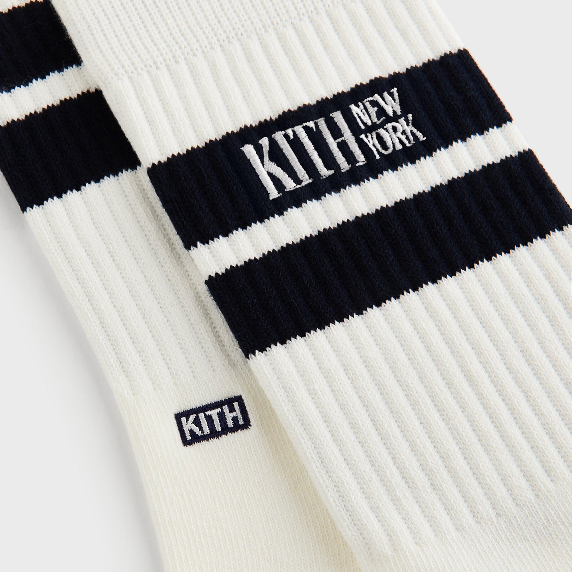 Close-up detail of Kith Calf Stripe Socks in Silk showing ribbed knit, navy stripe, and embroidered Kith tab