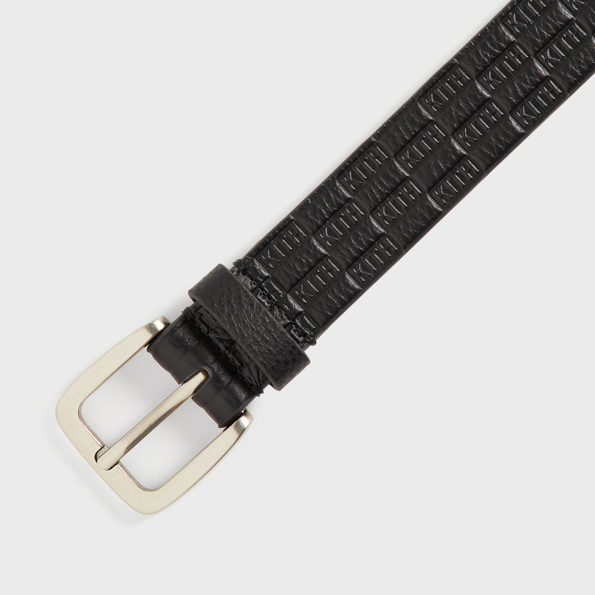 Kith Monogram Tumbled Leather Belt in Black, close-up of silver prong buckle and embossed monogram texture