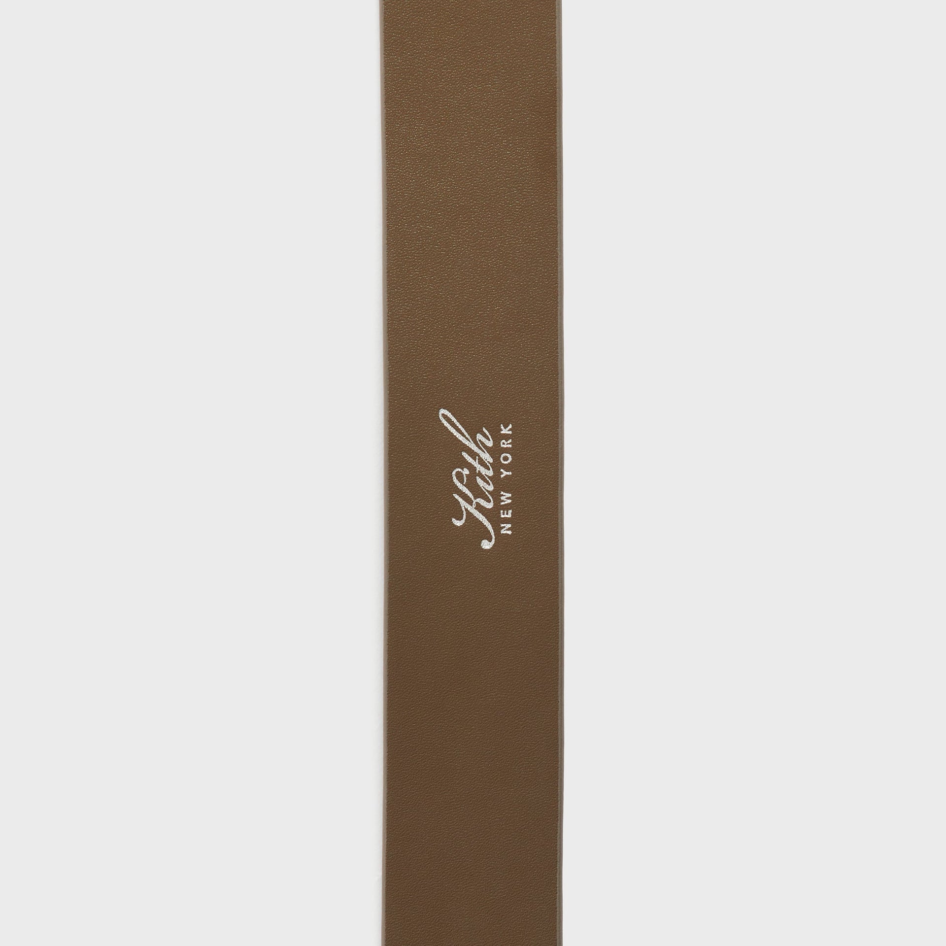 Kith Monogram Suede Belt in Java, close-up of the smooth java leather reverse with foil Kith New York logo stamp