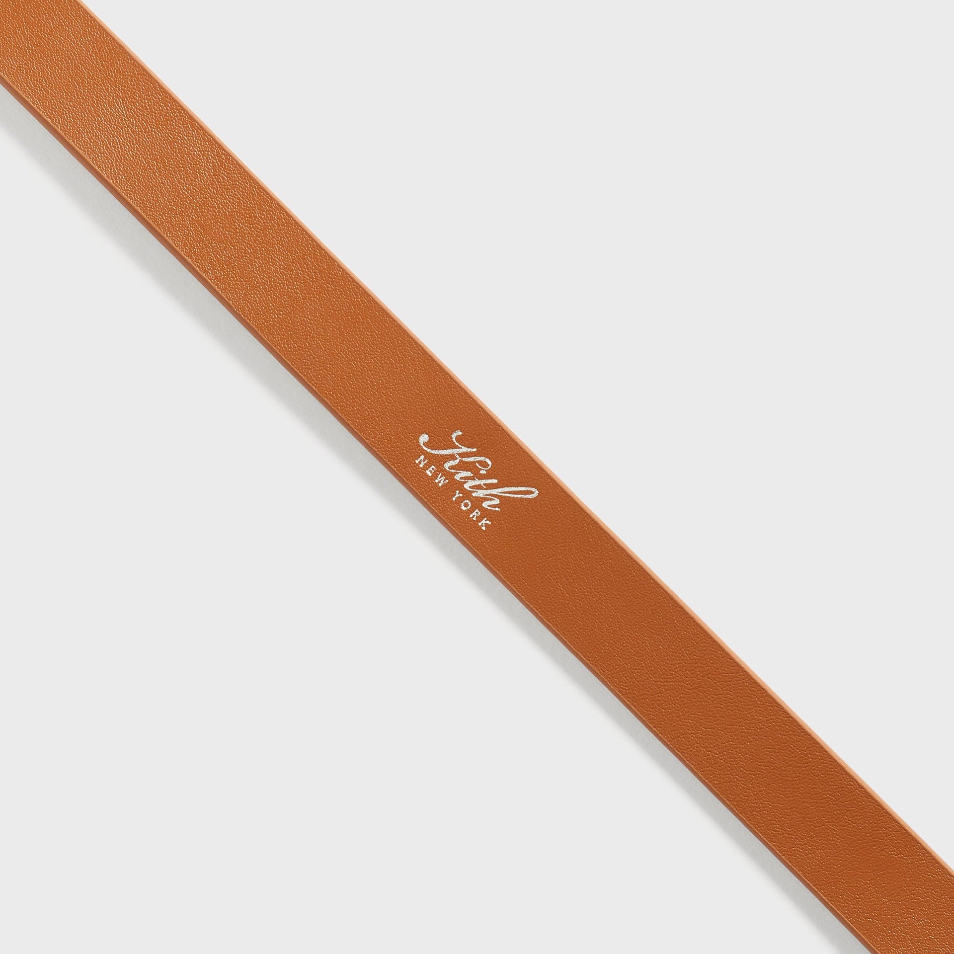 Close-up detail of the Kith Western Suede Belt in Argil, showing the smooth leather reverse side with foil-stamped Kith New York logo