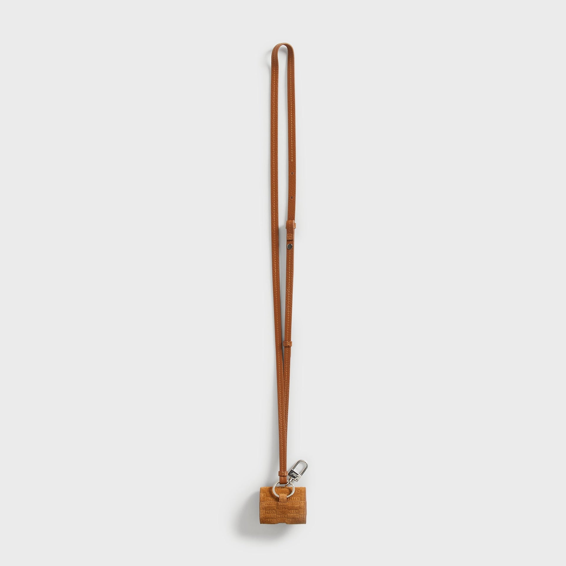 Kith Monogram Suede AirPod Case in tan, alternate view of the leather crossbody lanyard strap with adjustable buckle and suede case