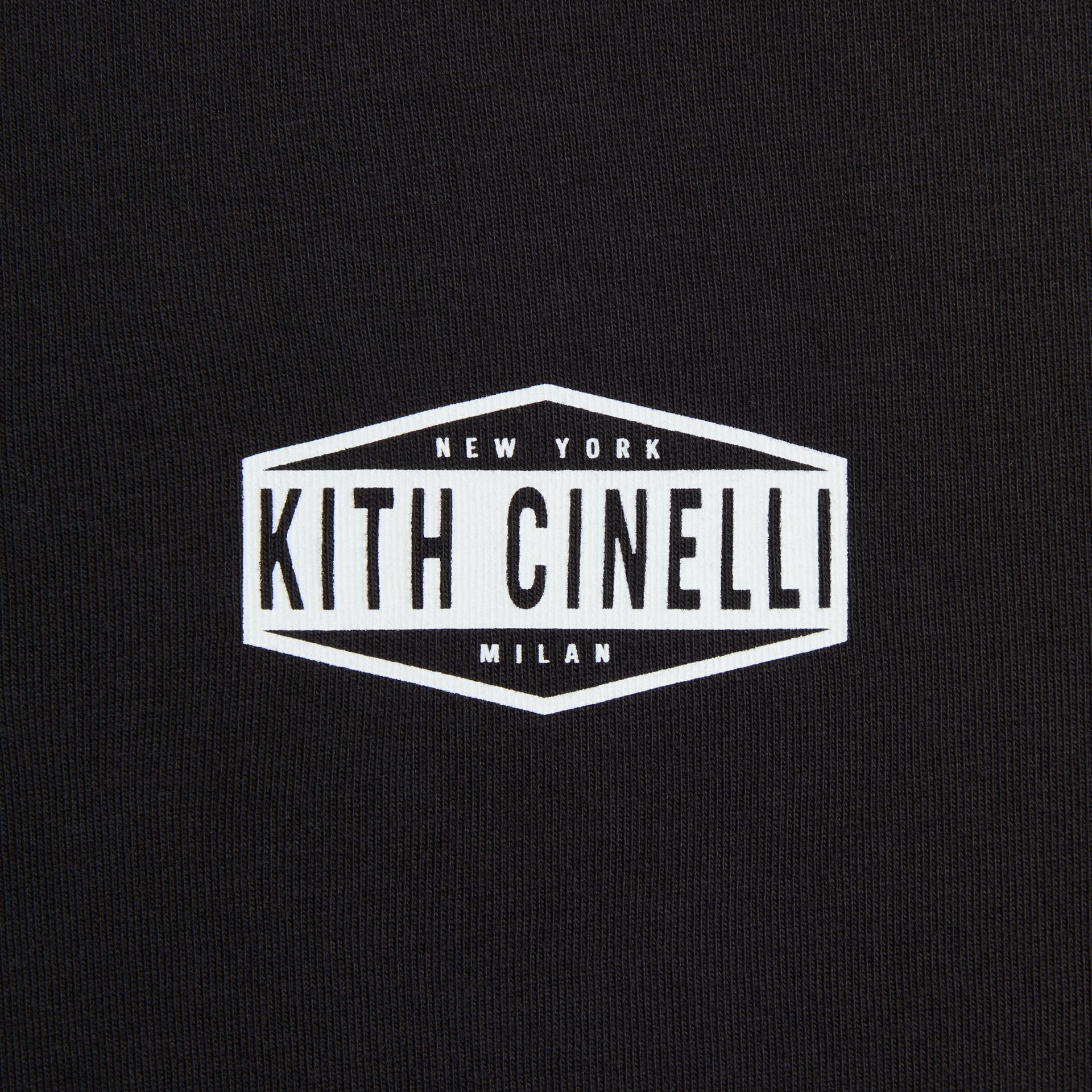 Kith for Cinelli Ciclismo Tee close-up of white Kith Cinelli New York Milan hexagonal chest badge on black cotton