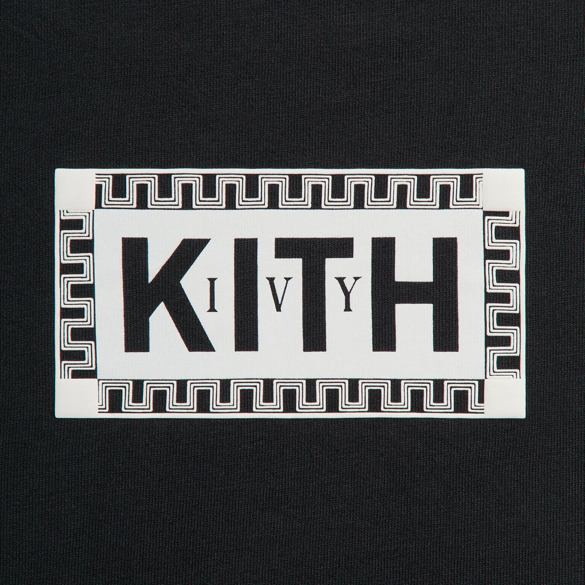 Close-up of Kith Ivy box logo with Greek-key border in cream on black tee chest