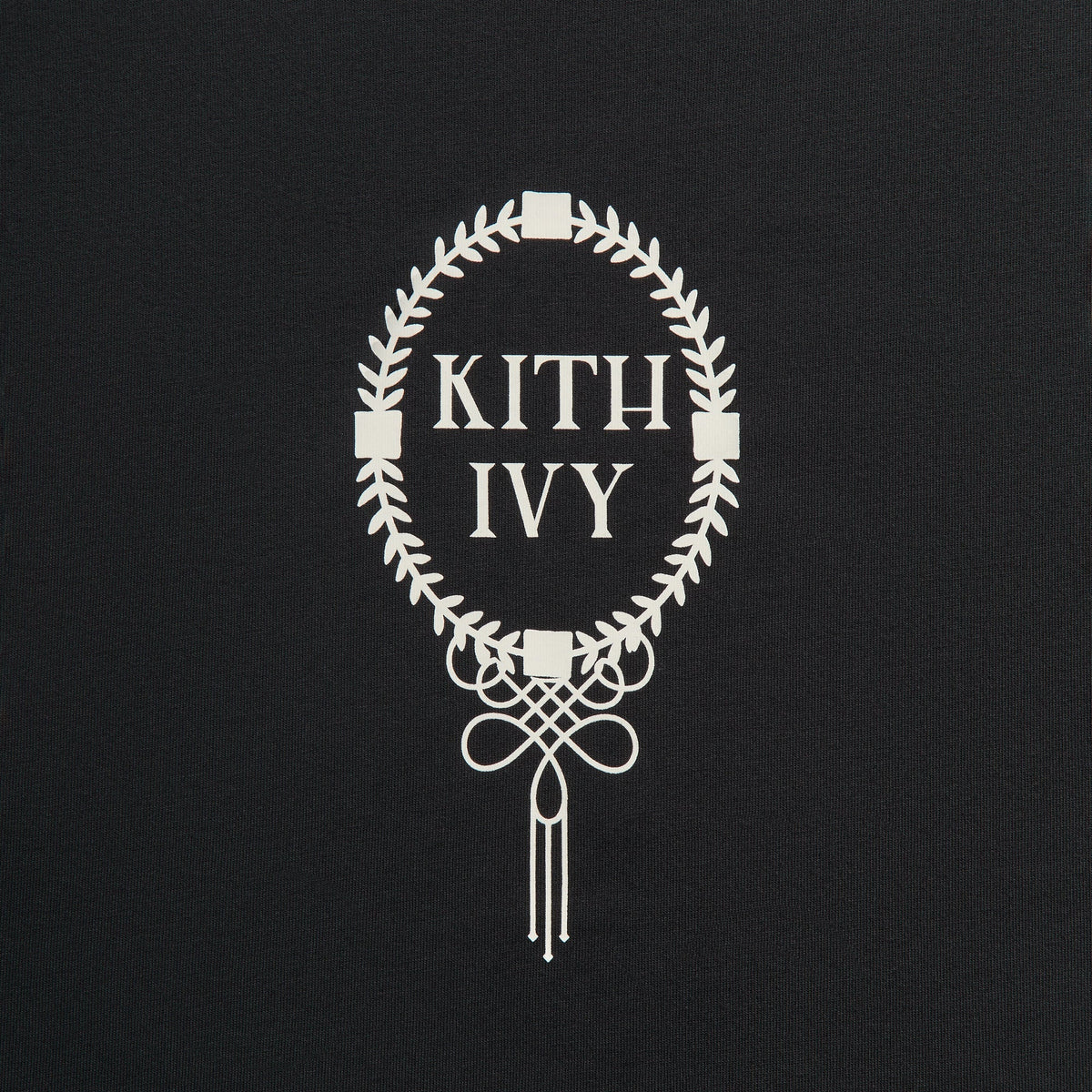 Close-up of cream laurel-wreath KITH IVY emblem with knot tassel on black Kith Ivy Tee chest