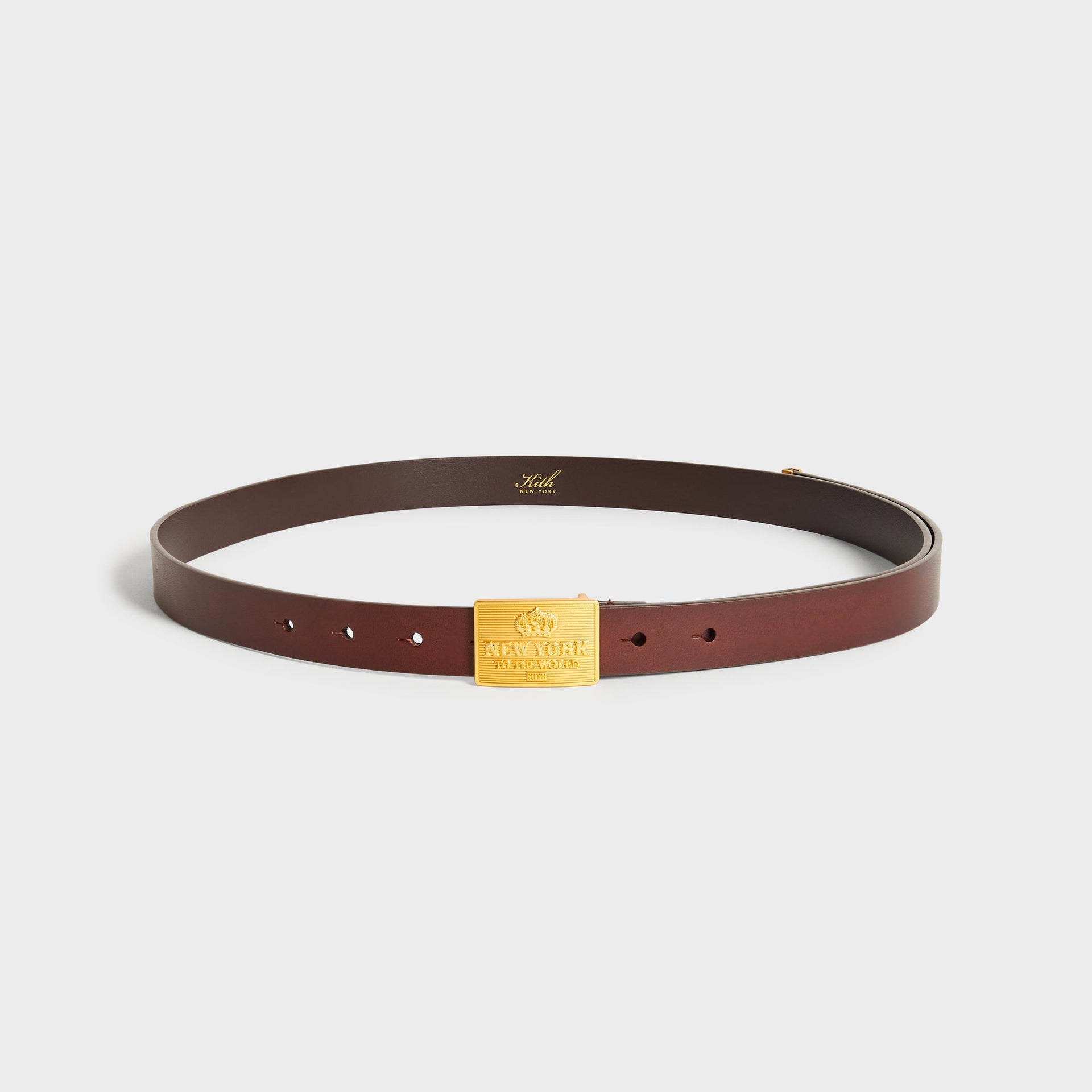 Kith New York Plaque Belt in Walnut leather, coiled to show the gold-tone New York to the World buckle plaque
