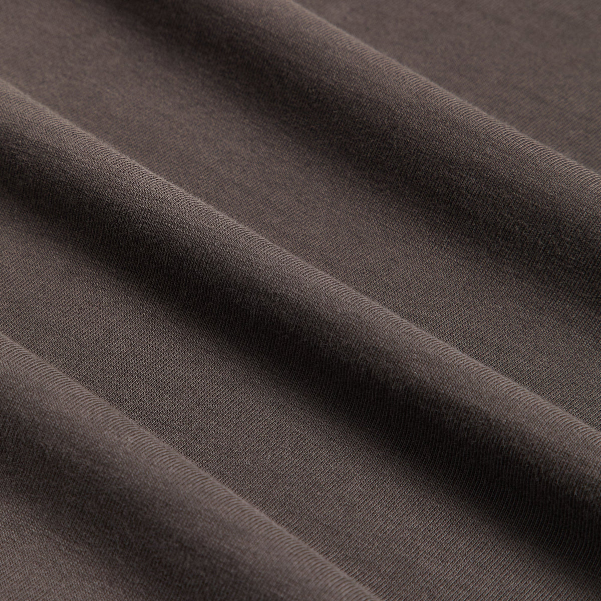 Fabric detail of Kith Treats Pumpkin Harvest Long Sleeve Tee in Kindling, dark brown cotton jersey folds