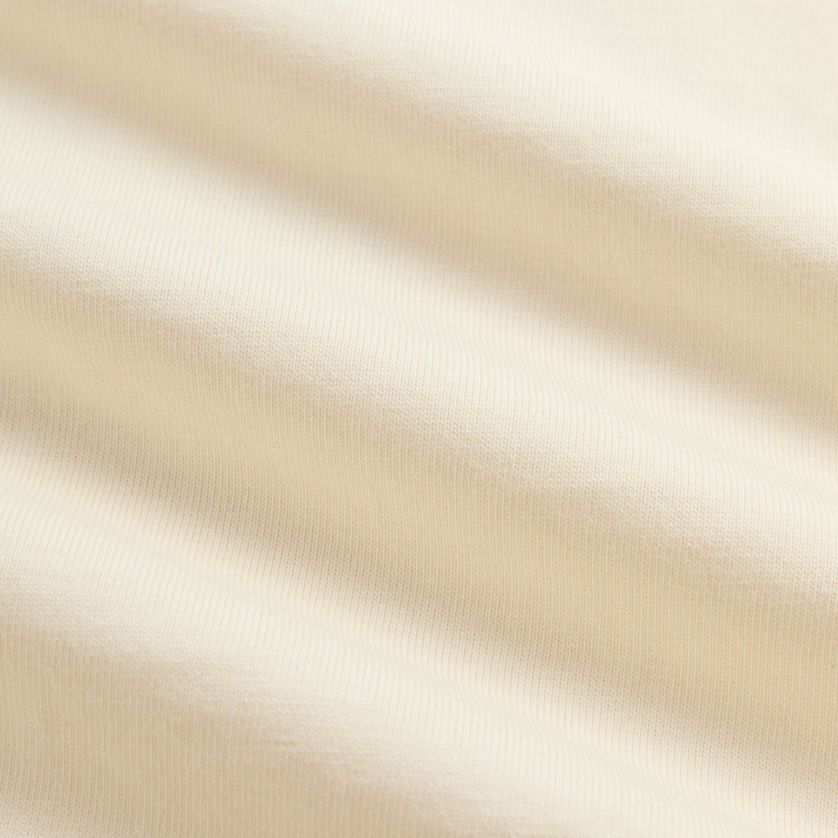 Fabric detail of Kith Kids Treats Pumpkin Harvest Pocket Tee in Sandrift, soft cream cotton jersey texture