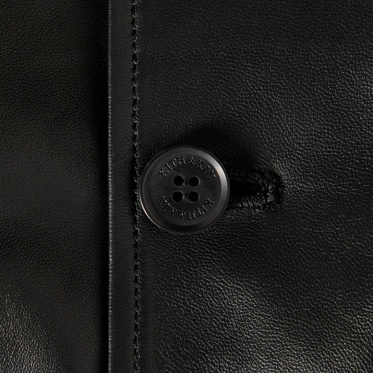 Close-up of the Kith & Kin engraved button on the Vivien leather corset jacket in black