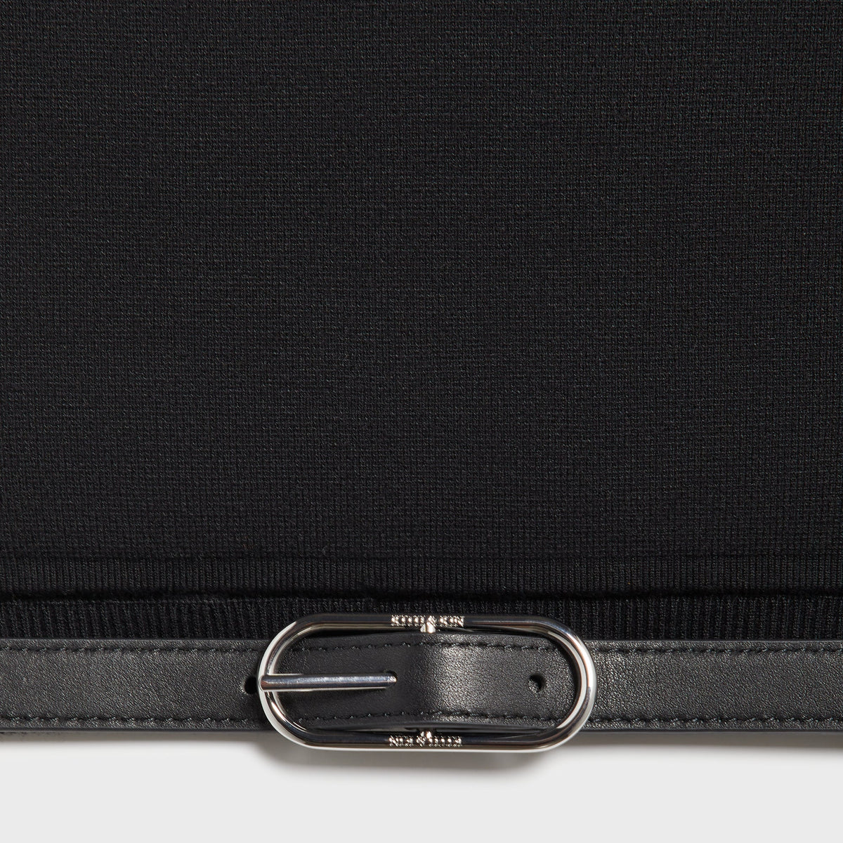 Close-up of the leather belt buckle hardware at the hem of the Kith Aria belt tank