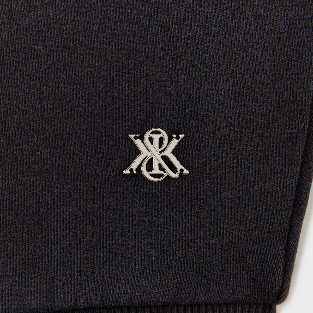 Close-up of the metal K charm hardware on the Kith Opal moto dolman short sleeve top