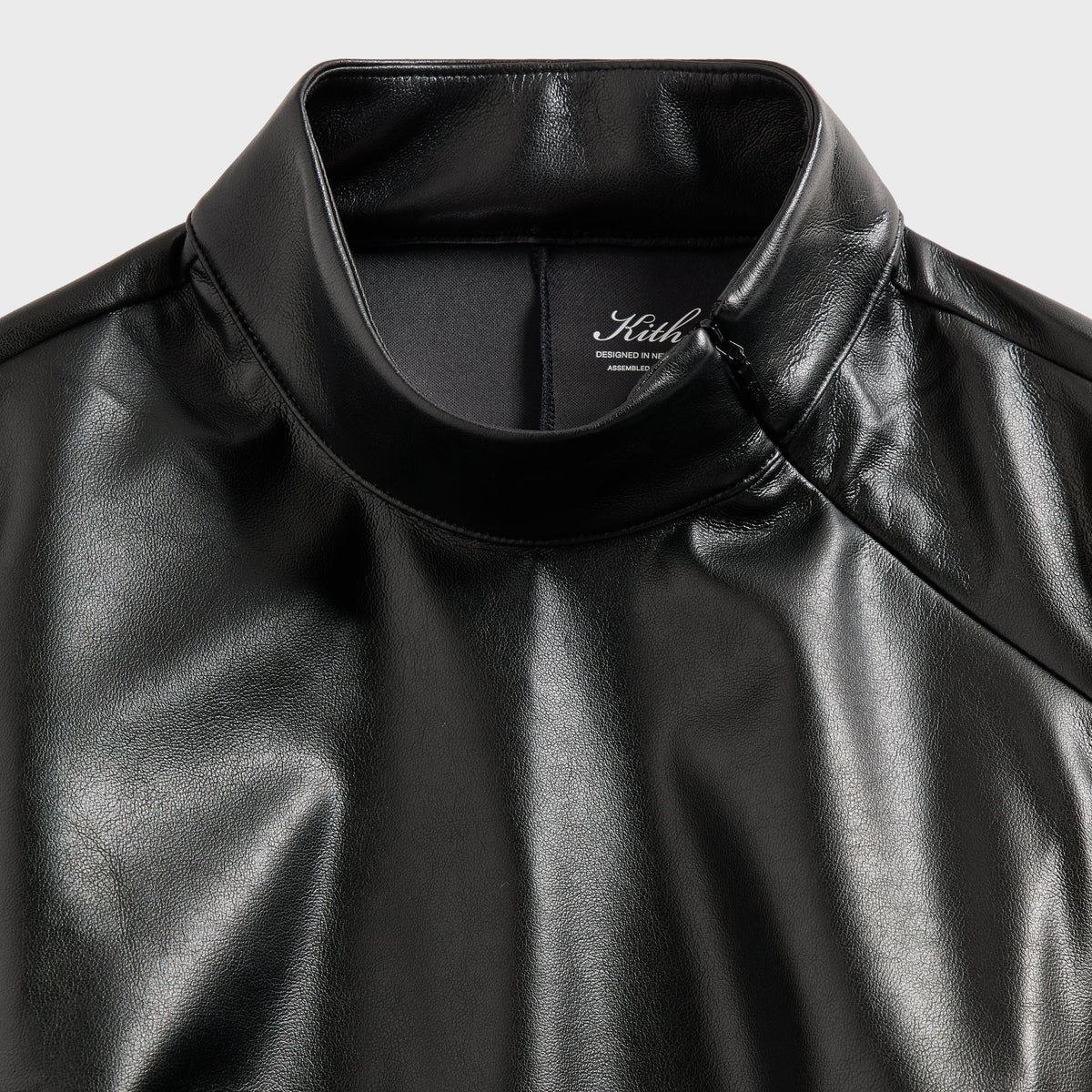 Close-up of the asymmetrical zip collar on the Kith Duri faux leather top in black