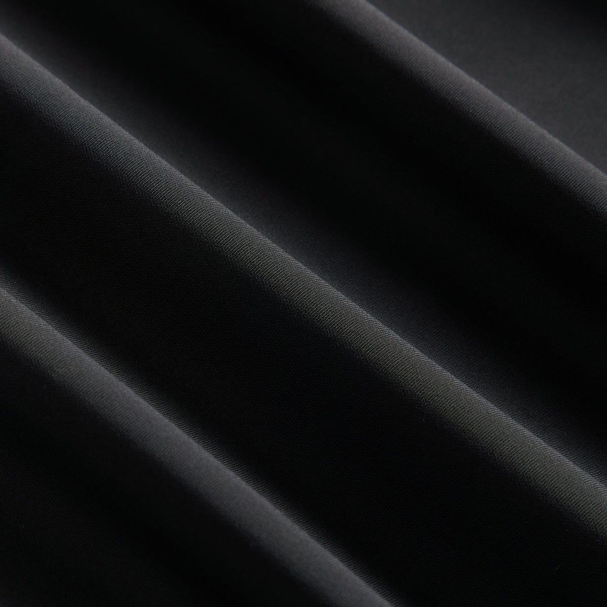 Close-up of the black stretch fabric texture on the Kith Women Nabi curved seam long sleeve jacket