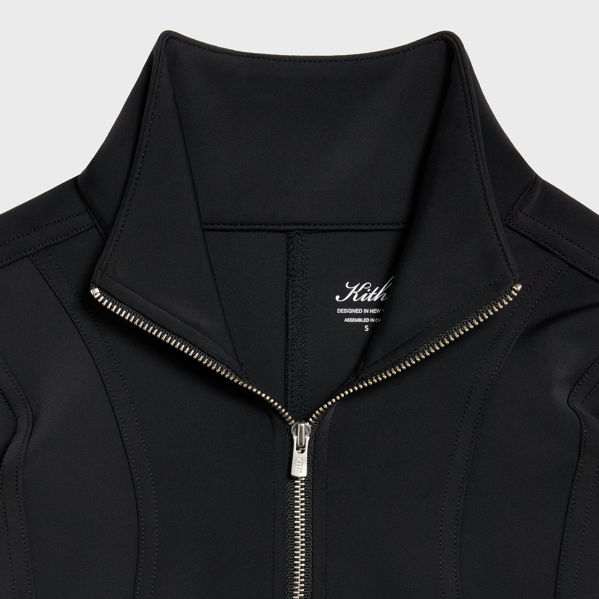 Close-up of the Kith Nabi jacket collar and zipper pull with Kith logo tag at the neck
