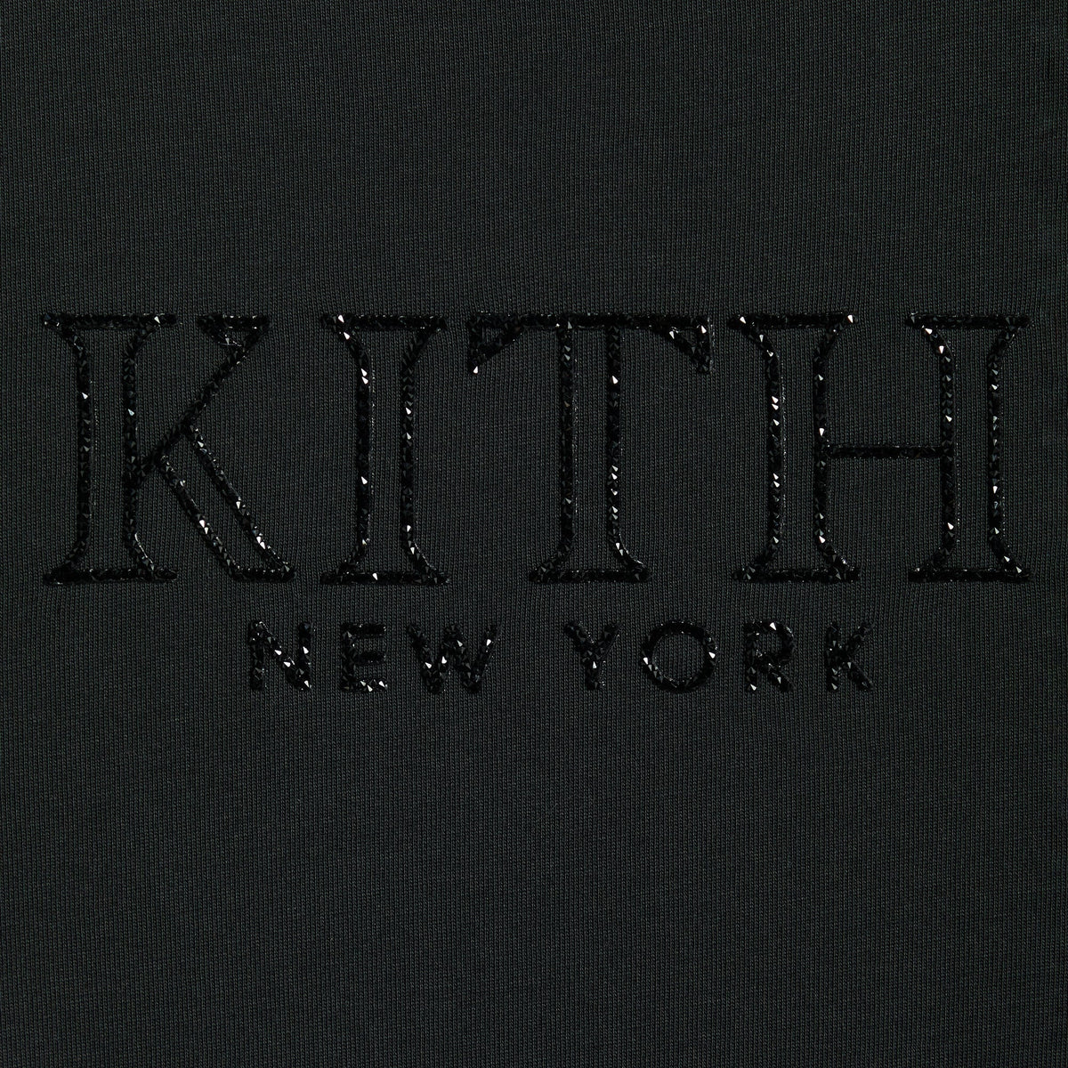 Close-up of the crystal-embellished Kith New York serif logo on the Mulberry vintage tee in black