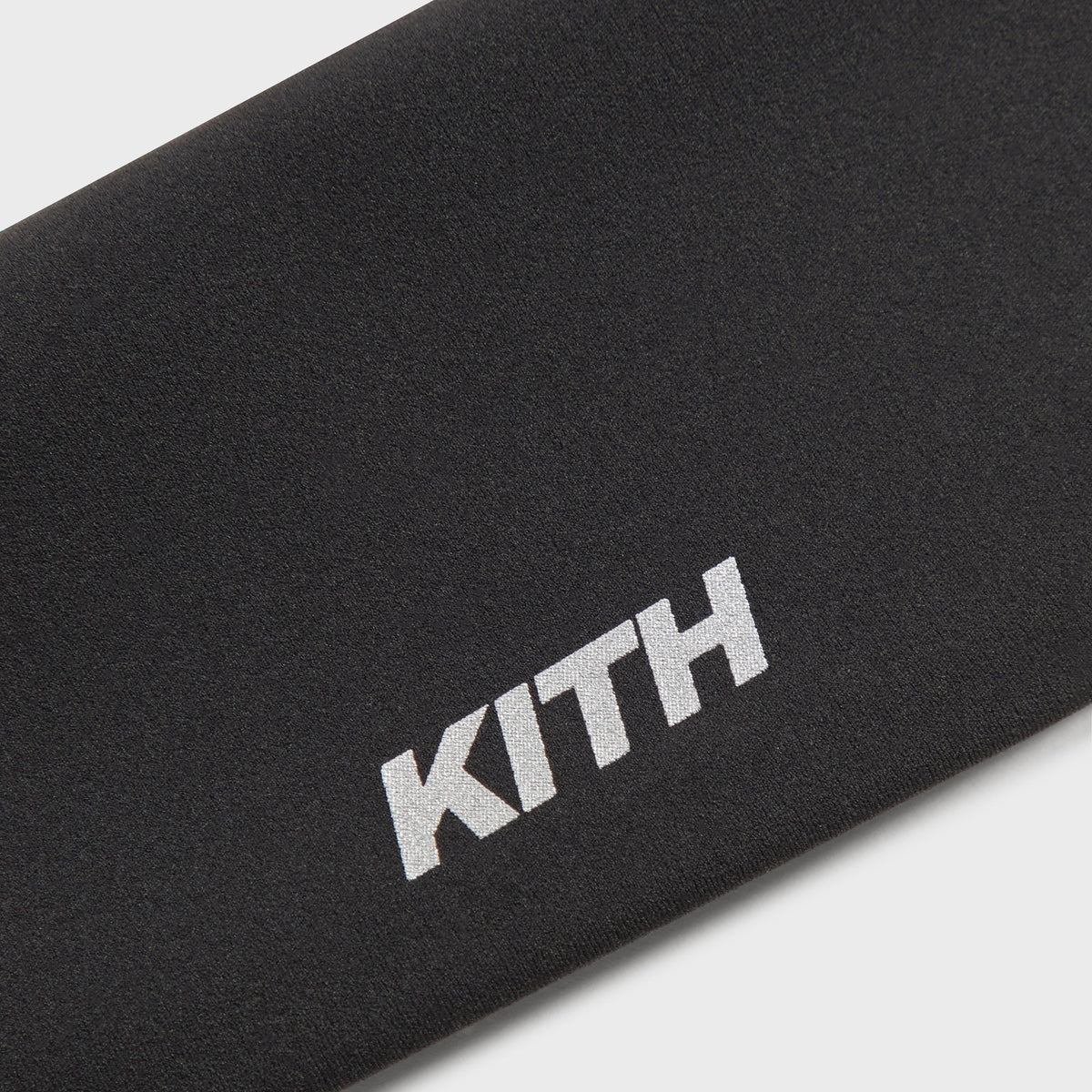 Close-up of Kith Women's Active Headband reflective Kith wordmark on black stretch fabric