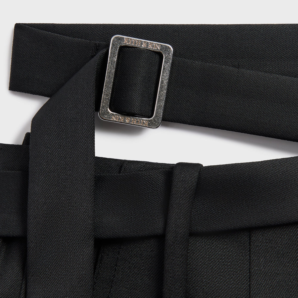 Close-up of the Kith & Kin engraved buckle on the waist strap of the Tallis suiting trouser