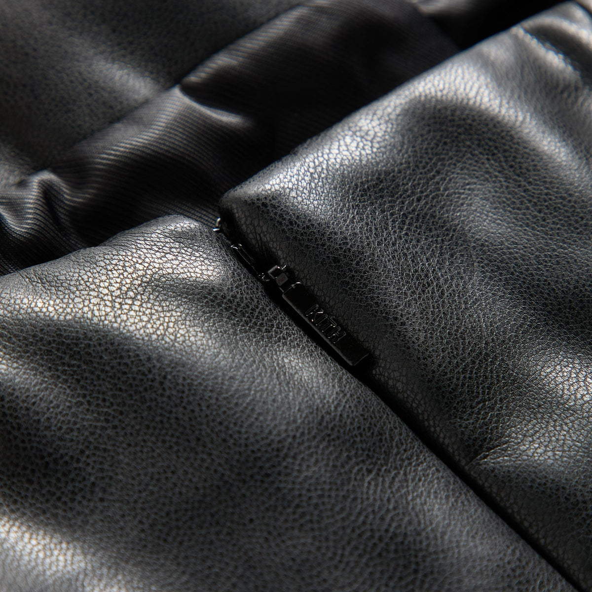 Close-up of the back zipper pull engraved with Kith on the Saja faux leather mini dress