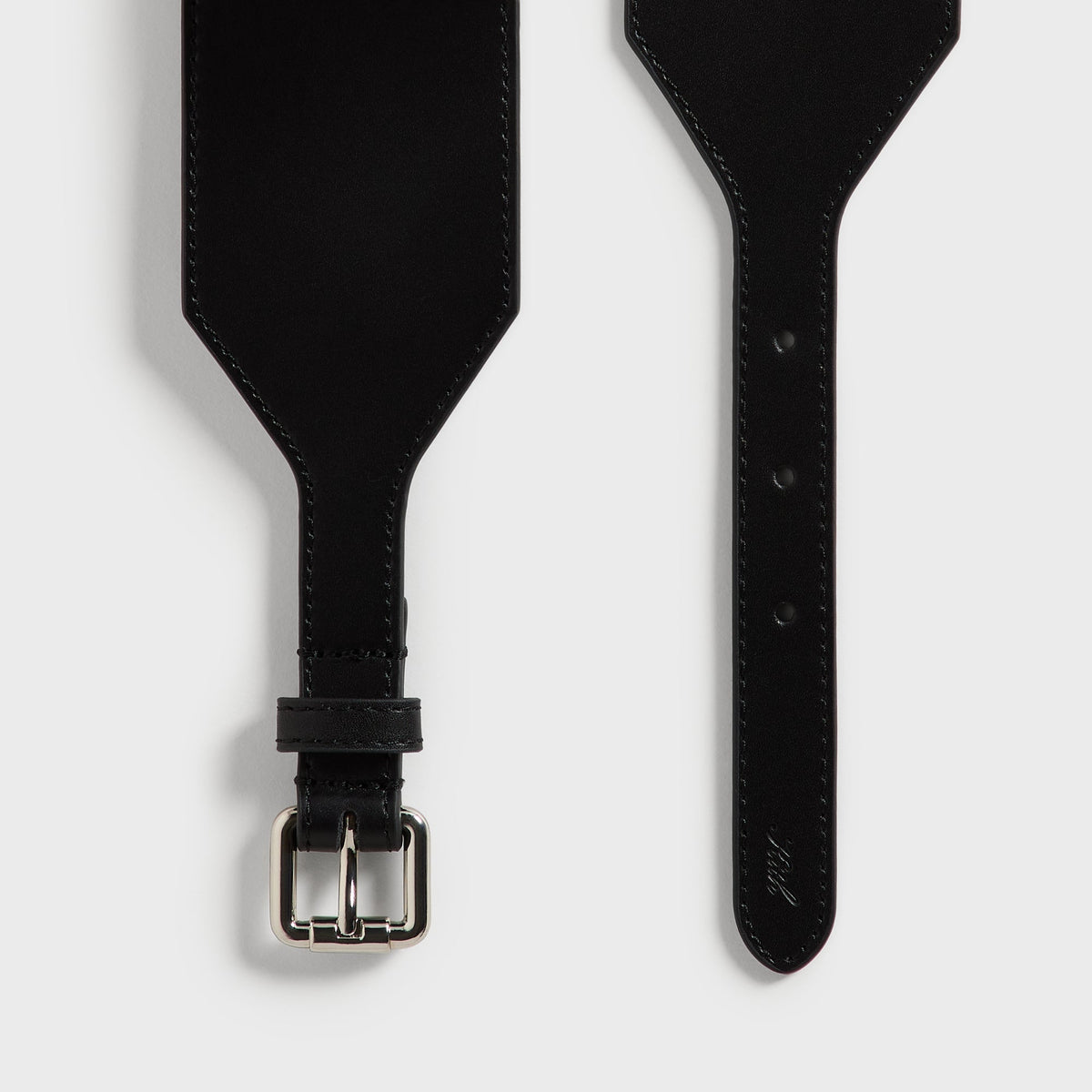 Close-up of both tapered ends of the Kith belt in black leather, showing the buckle strap and embossed Kith script