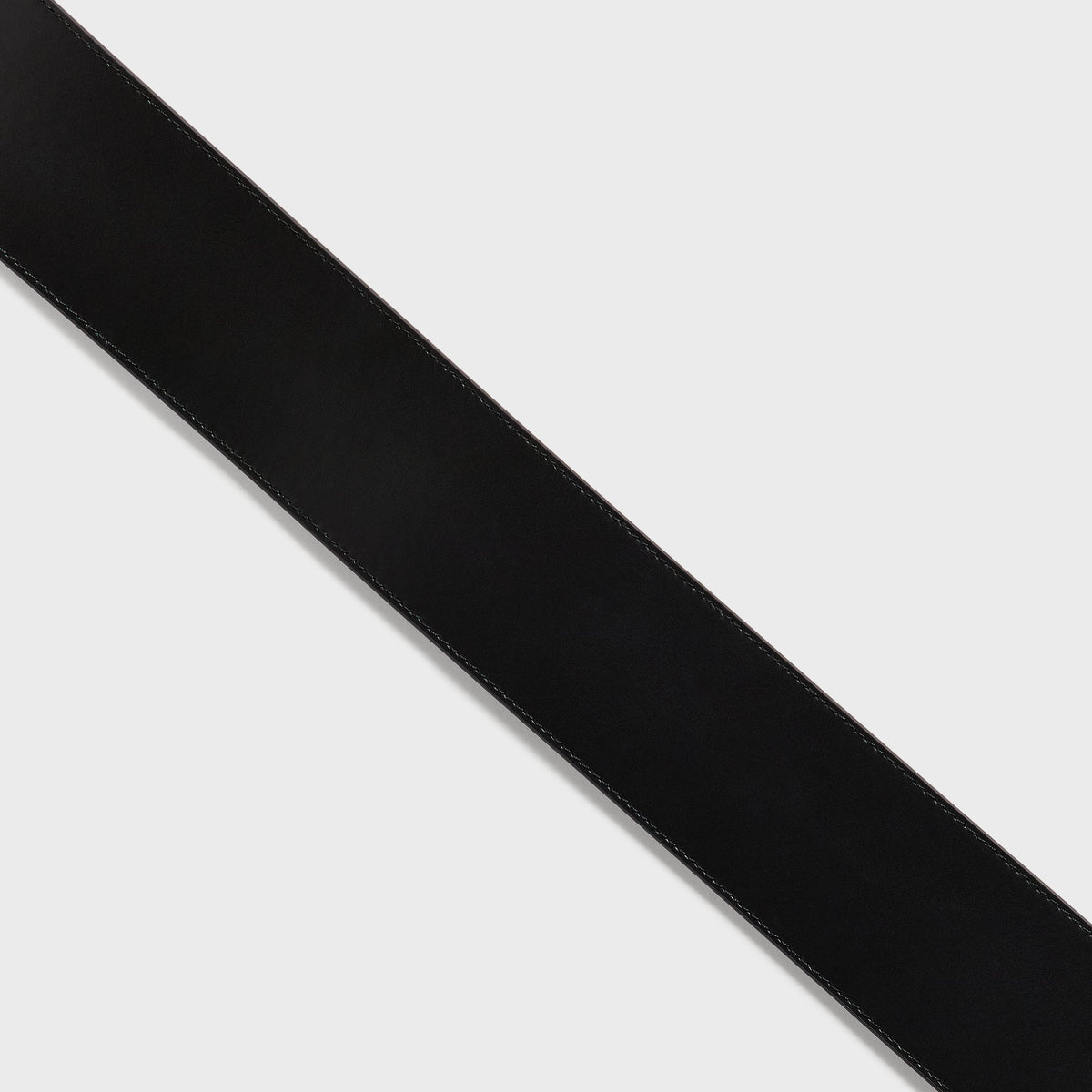 Close-up of the smooth black leather surface and stitched edge on the Kith Women tapered belt