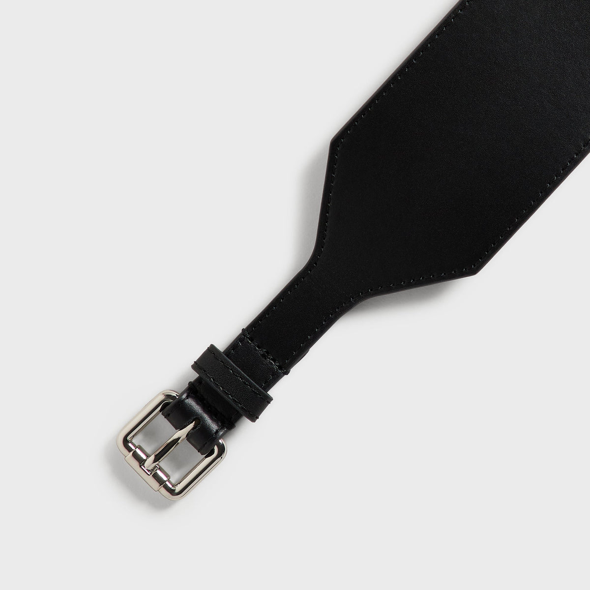 Close-up of the silver roller buckle and keeper loop on the Kith Women tapered belt in black leather