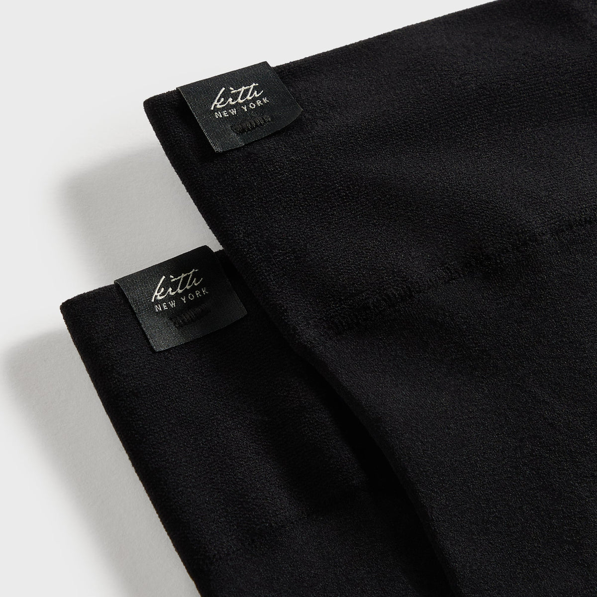 Close-up of the woven 'kith new york' labels on the black Sheer Stirrup Thigh-High Socks