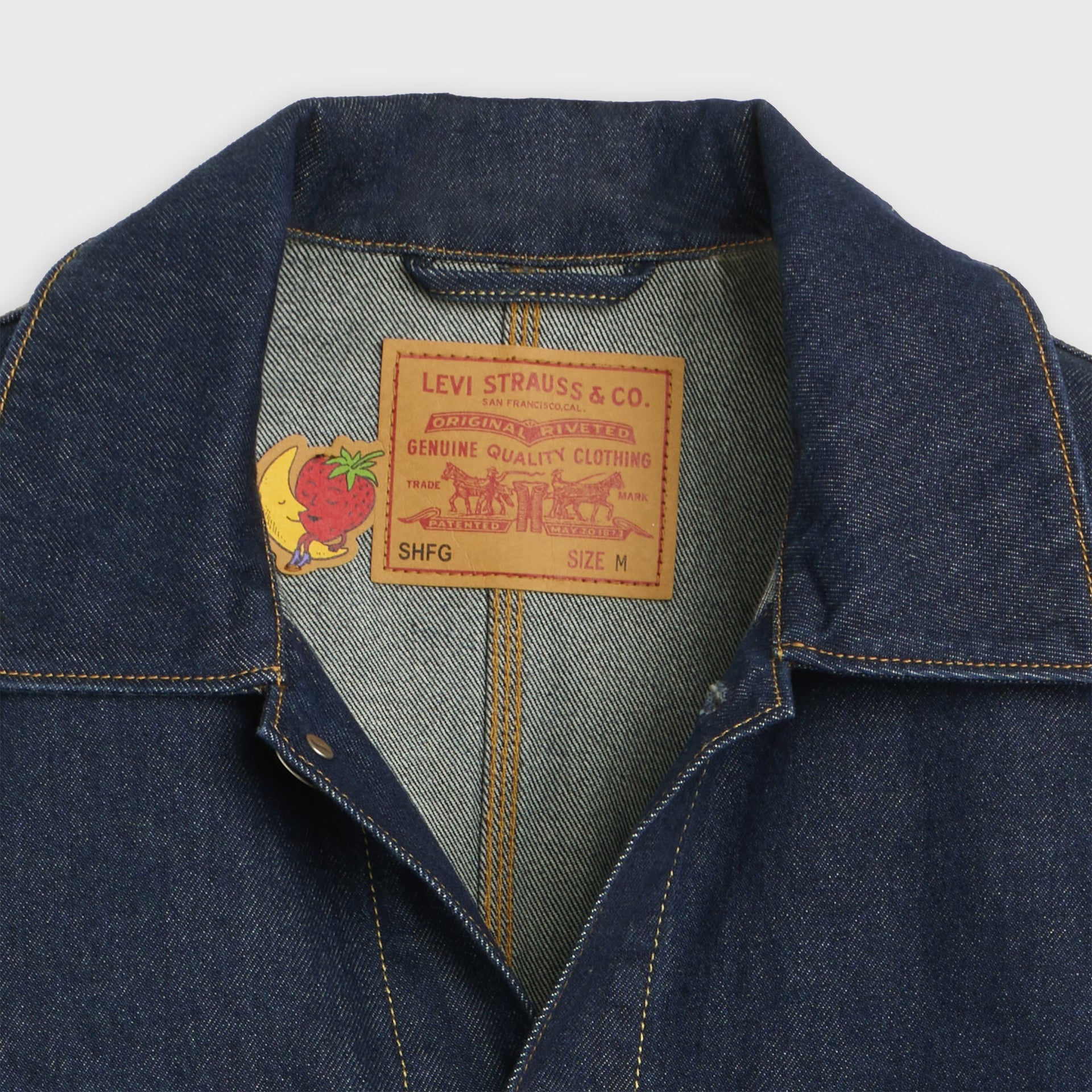 Collar detail of Levi's x Sky High Farm chore coat with inside 'Genuine Quality' SHFG label and banana-and-strawberry mascot
