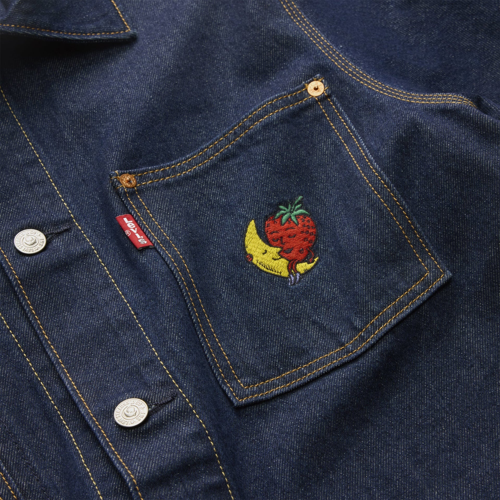 Close-up of Levi's x Sky High Farm chore coat chest pocket with red Levi's tab and embroidered banana-and-strawberry mascot