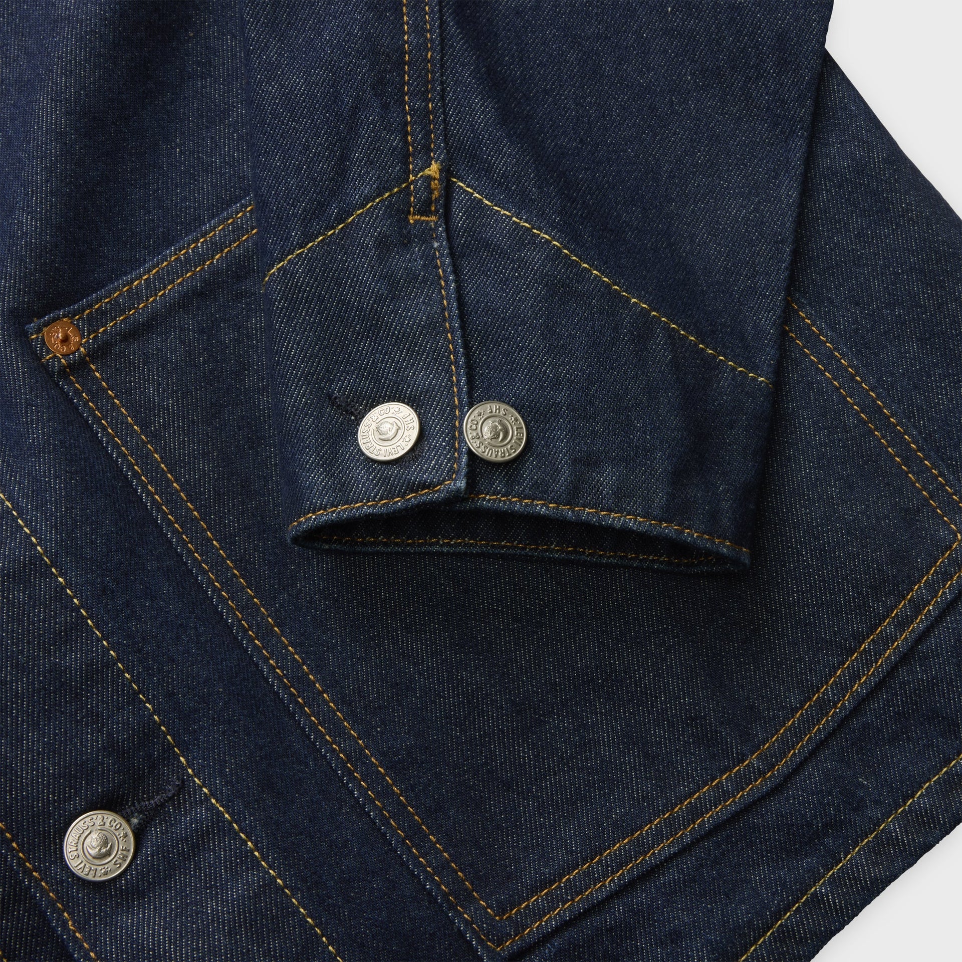Detail of Levi's x Sky High Farm dark rinse chore coat cuff and pocket with silver Levi's buttons and gold stitching