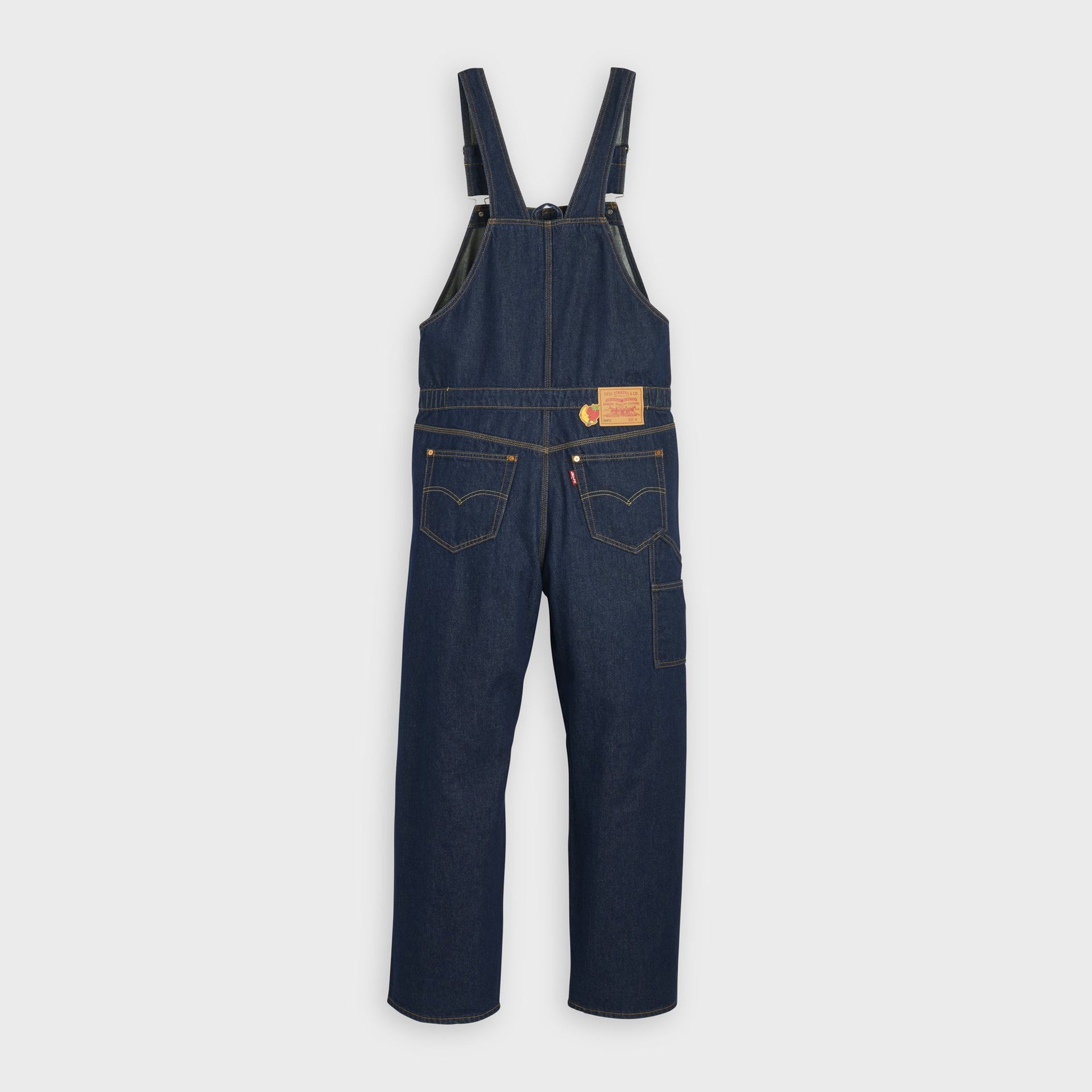 Back view of Levi's x Sky High Farm mid-indigo bib overalls with crossback straps, patch pockets and leather waist patch