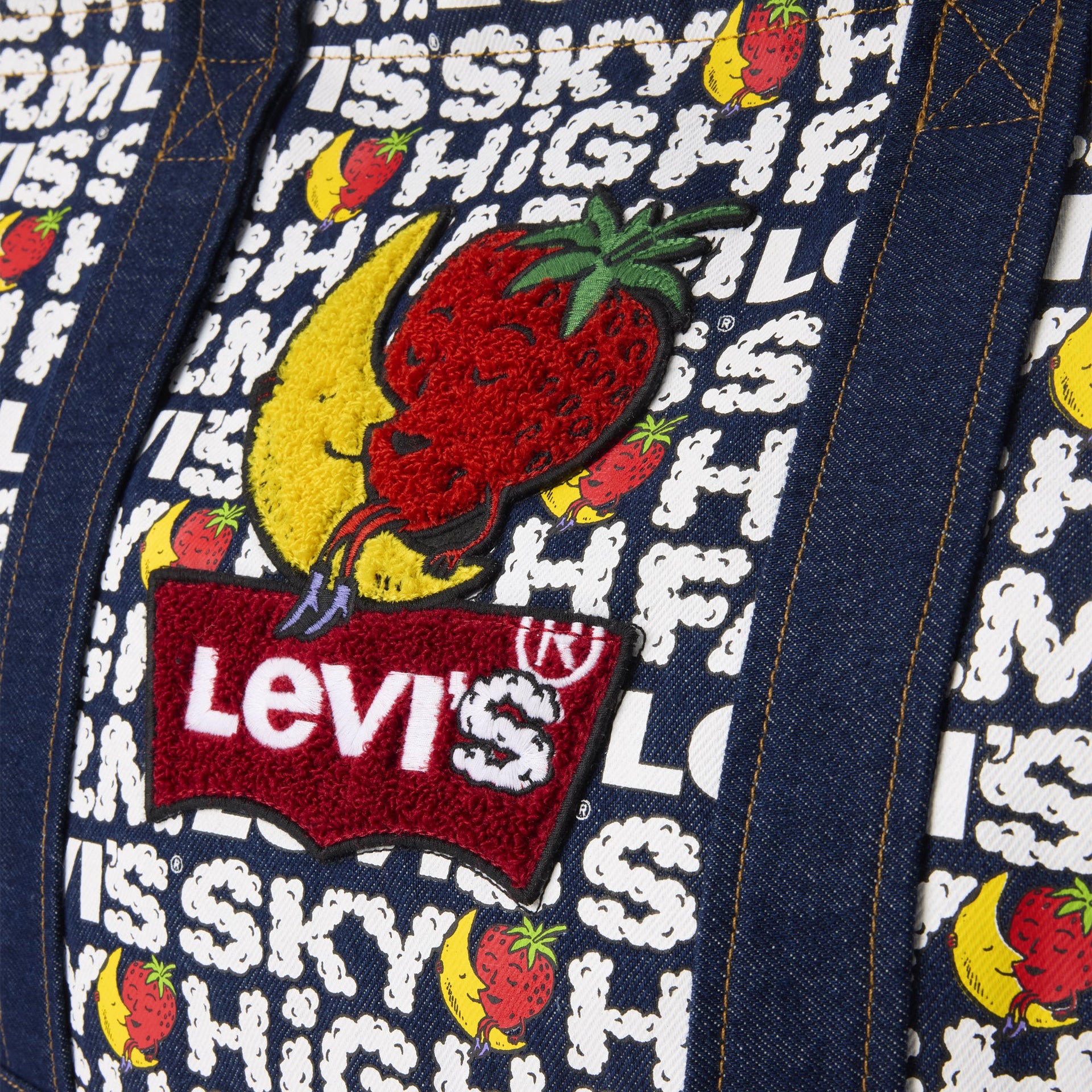 Close-up of Levi's x Sky High Farm tote chainstitch embroidery: yellow moon, red strawberry mascot and Levi's batwing logo