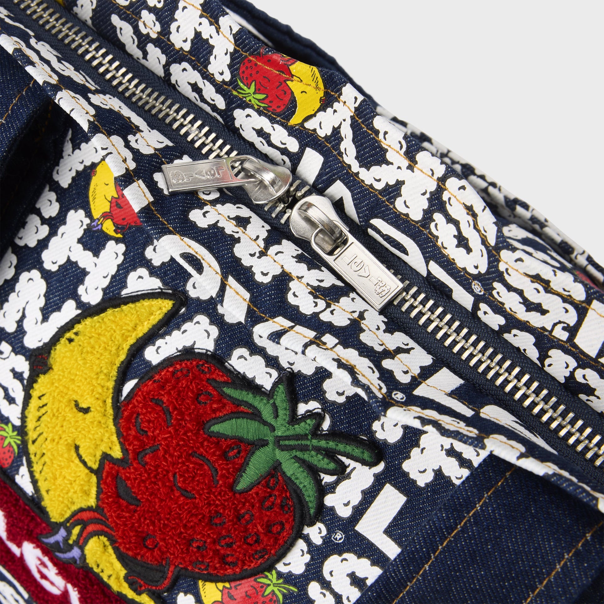 Detail of Levi's x Sky High Farm tote top zippers with double pulls and embroidered banana-and-strawberry mascot on logo print