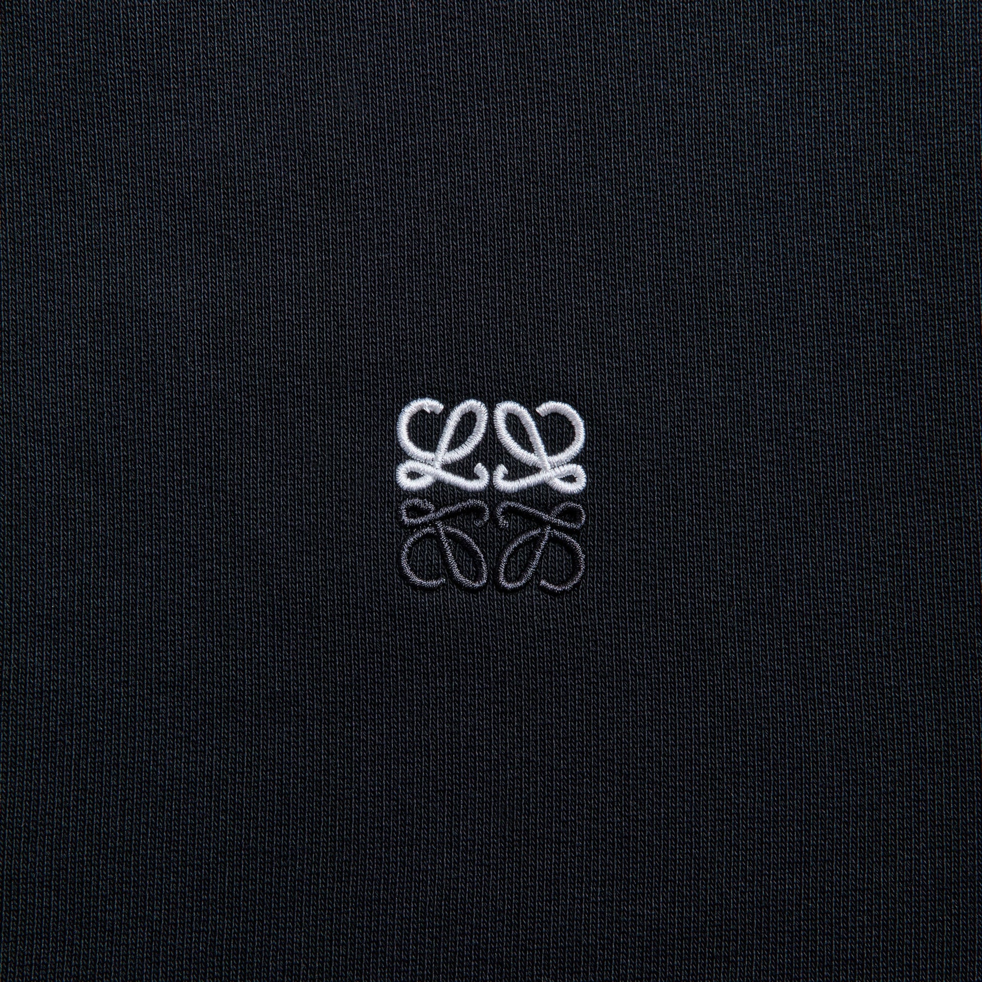 Detail of white and grey Anagram embroidery on Loewe washed black cotton hoodie