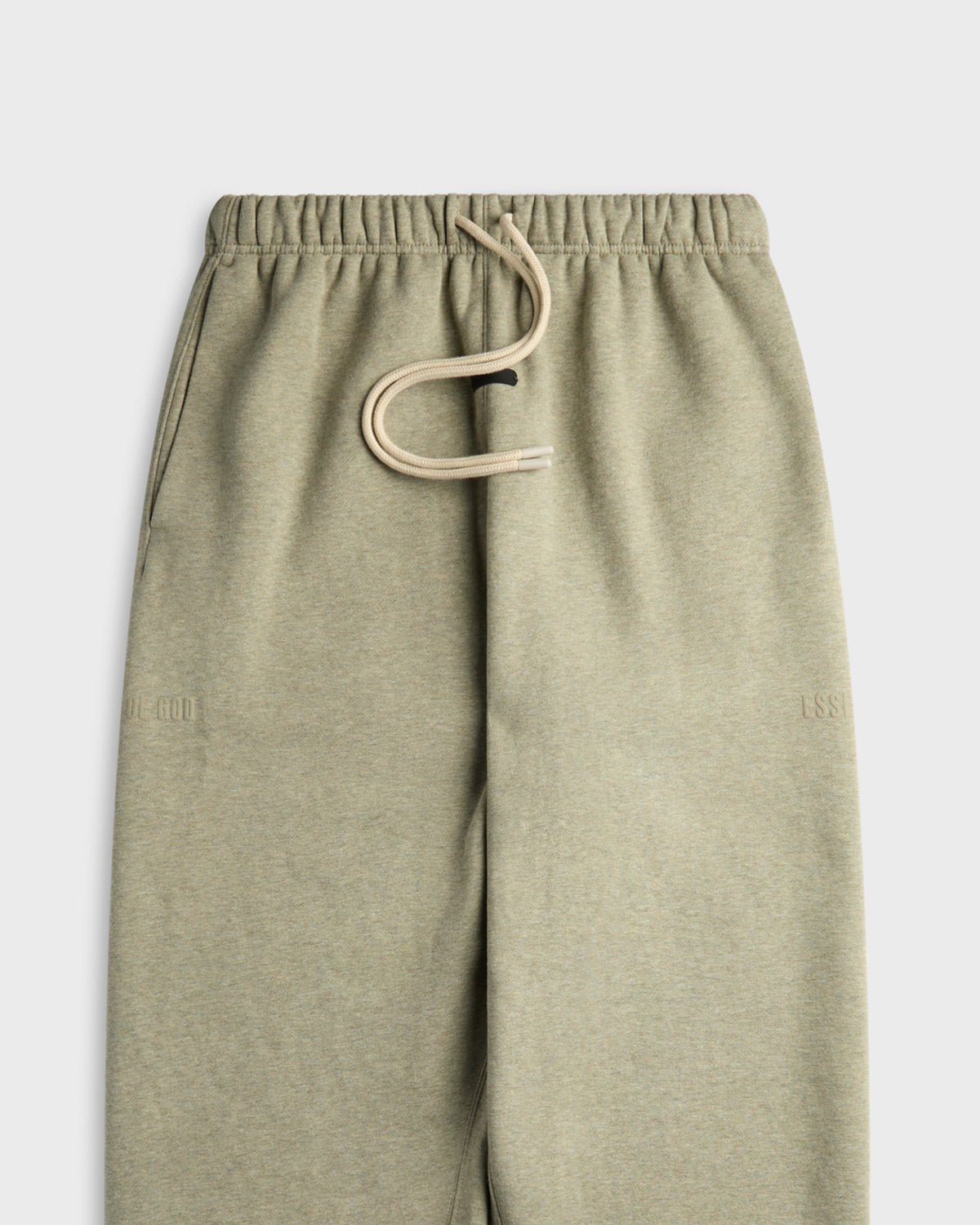Close-up of heather sage green Fear of God Essentials sweatpants with drawstring waistband and embossed logo text