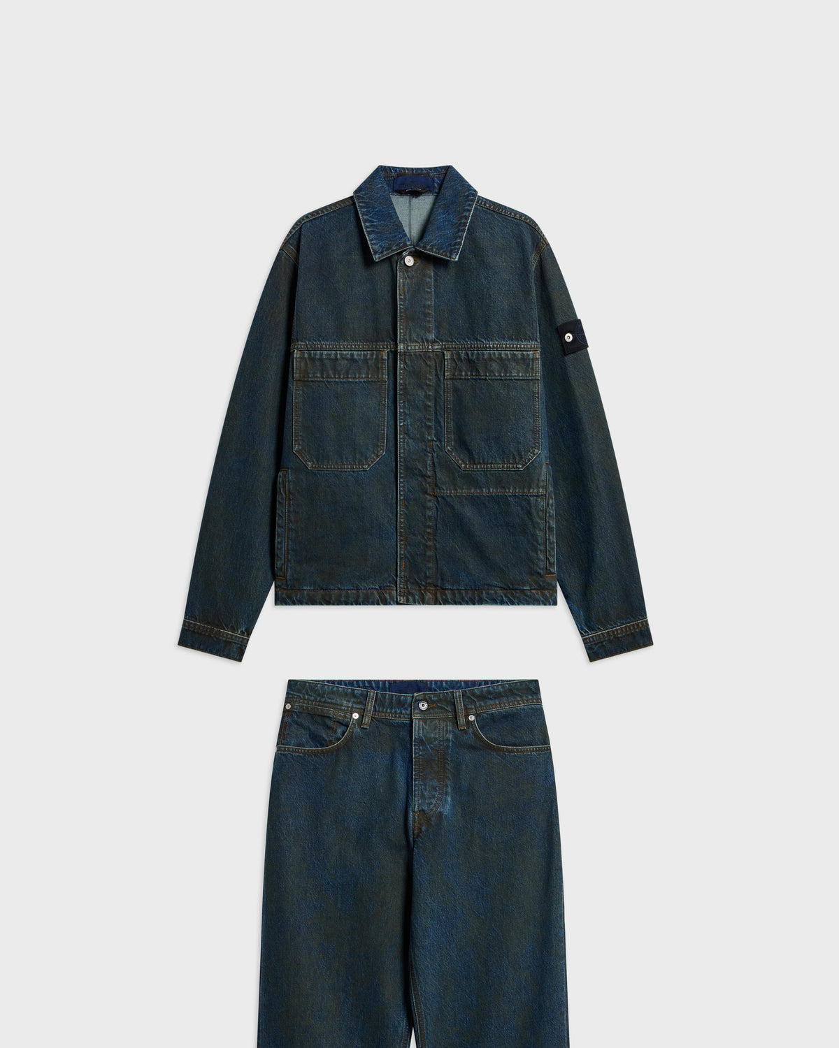 Stone Island dark blue washed denim chore jacket with sleeve patch and matching wide-leg jeans, flat lay