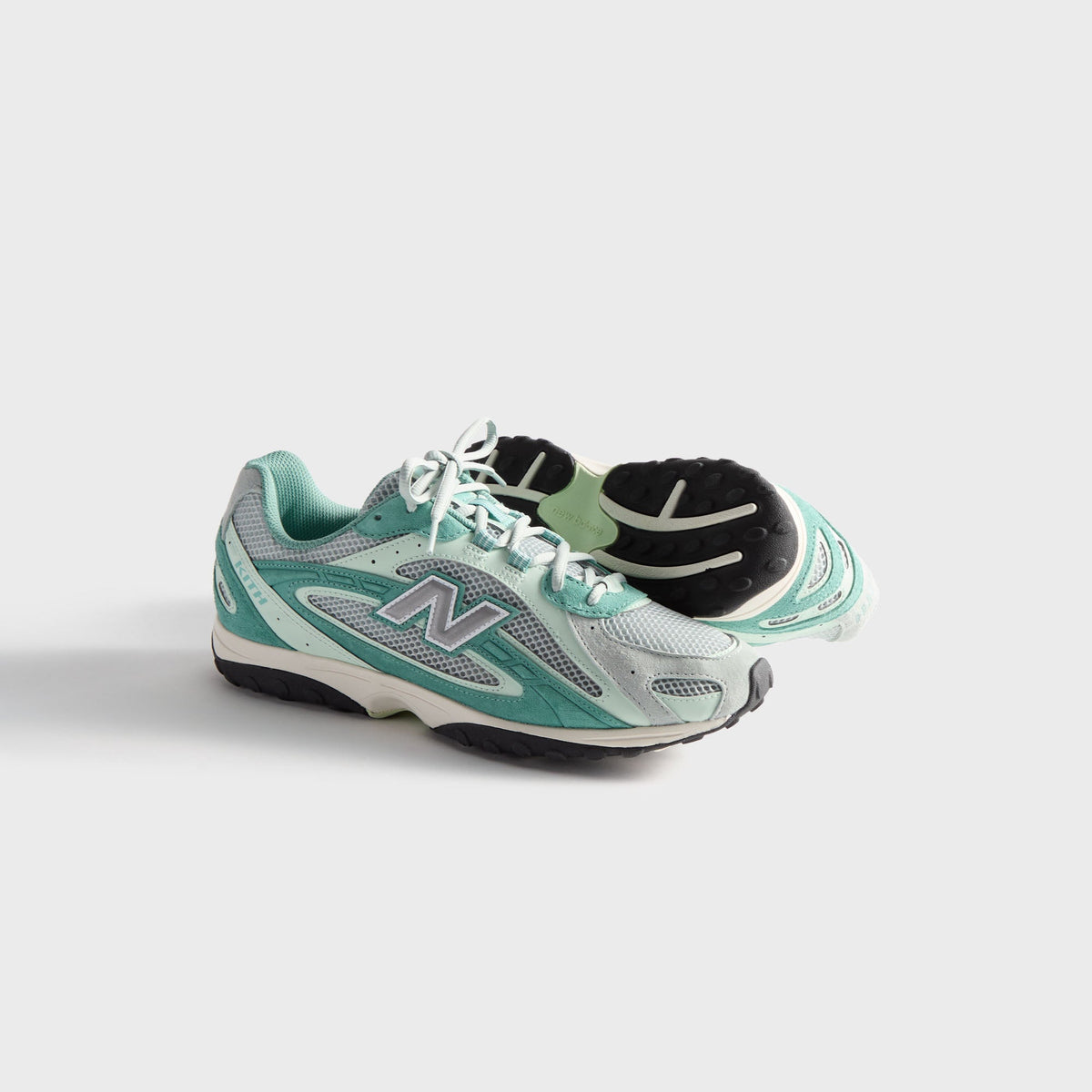 Kith & New Balance 204L in Bluebell, pair with one sneaker upright and one on its side revealing the outsole