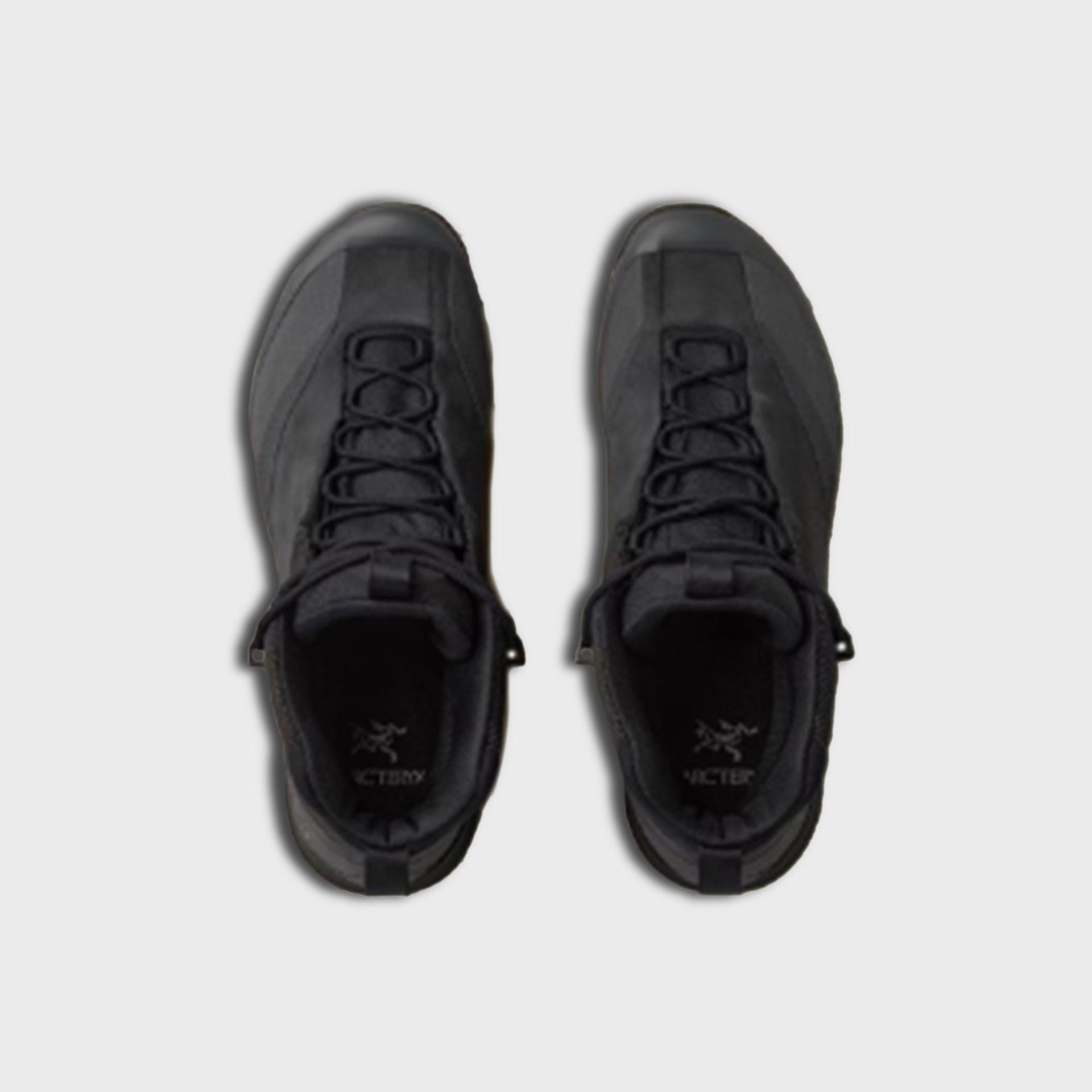 Pair of Arc'teryx Konseal Trek mid boots in black, top-down view showing crossed laces and Arc'teryx wordmark tongues