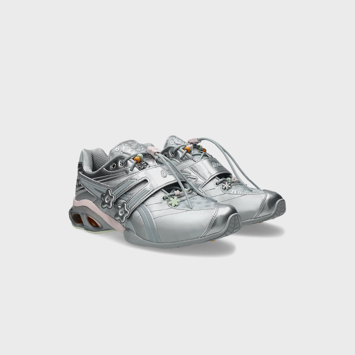 Pair of ASICS x Cecilie Bahnsen GEL-KINETIC FR sneakers in silver, angled front view with pastel floral lace charms
