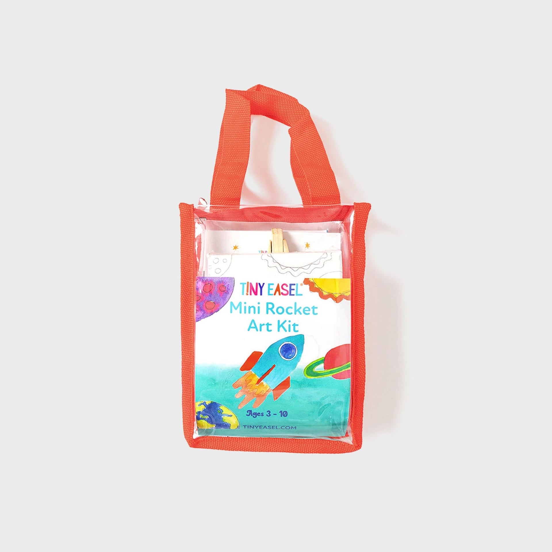 Tiny Easel Mini Rocket Art Kit in clear mini tote with orange trim, front view of watercolor rocket and planets packaging, ages 3-10