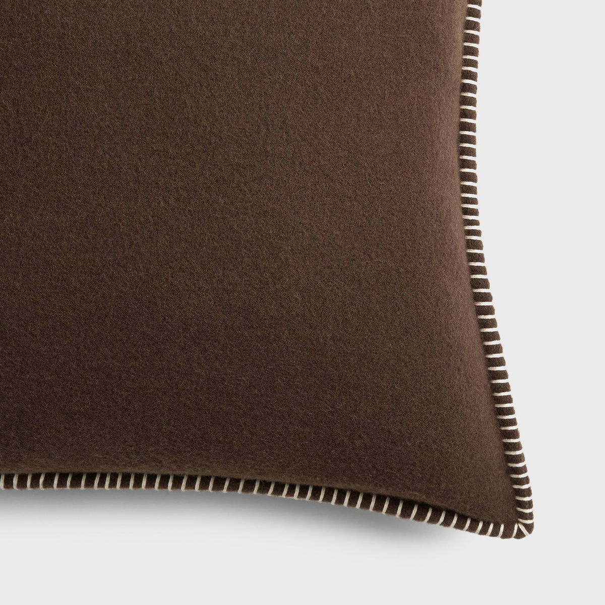 Tekla Lambswool Cushion in Walnut, close-up of the dark brown wool fabric and whipstitched edge